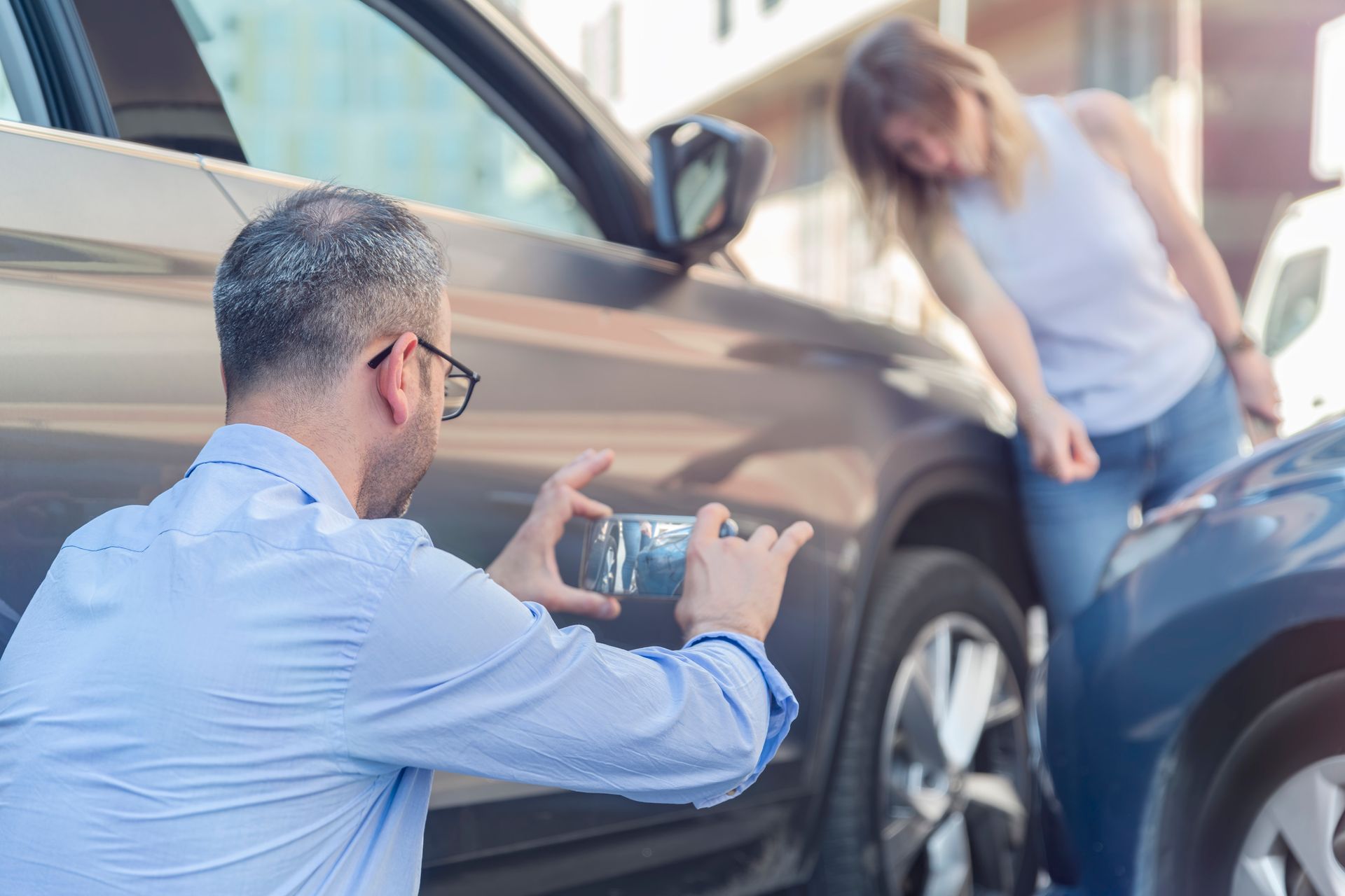 Driver photographing crash scene to document evidence for car insurance and legal claims.