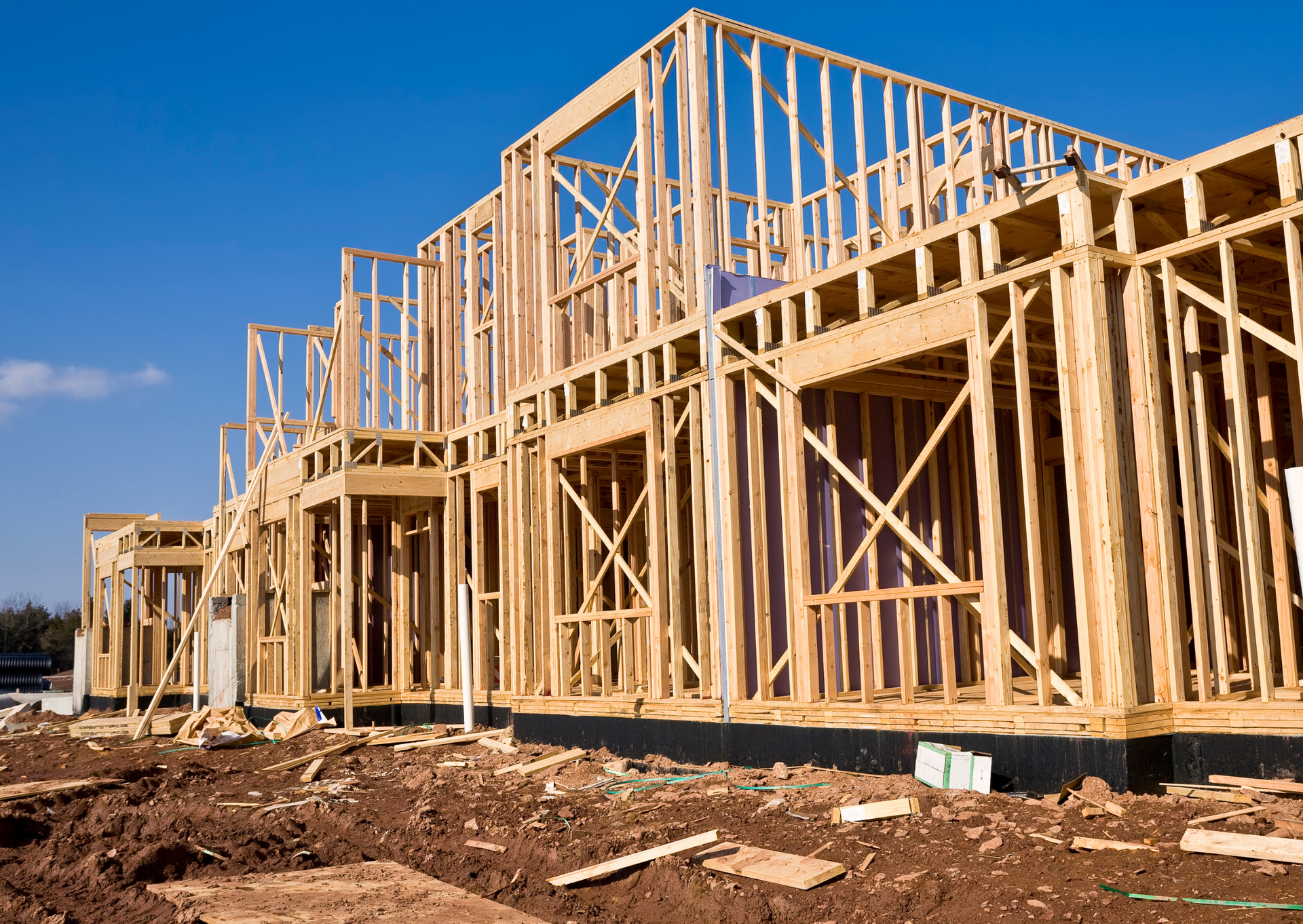 A large wooden house is being built in a construction site.