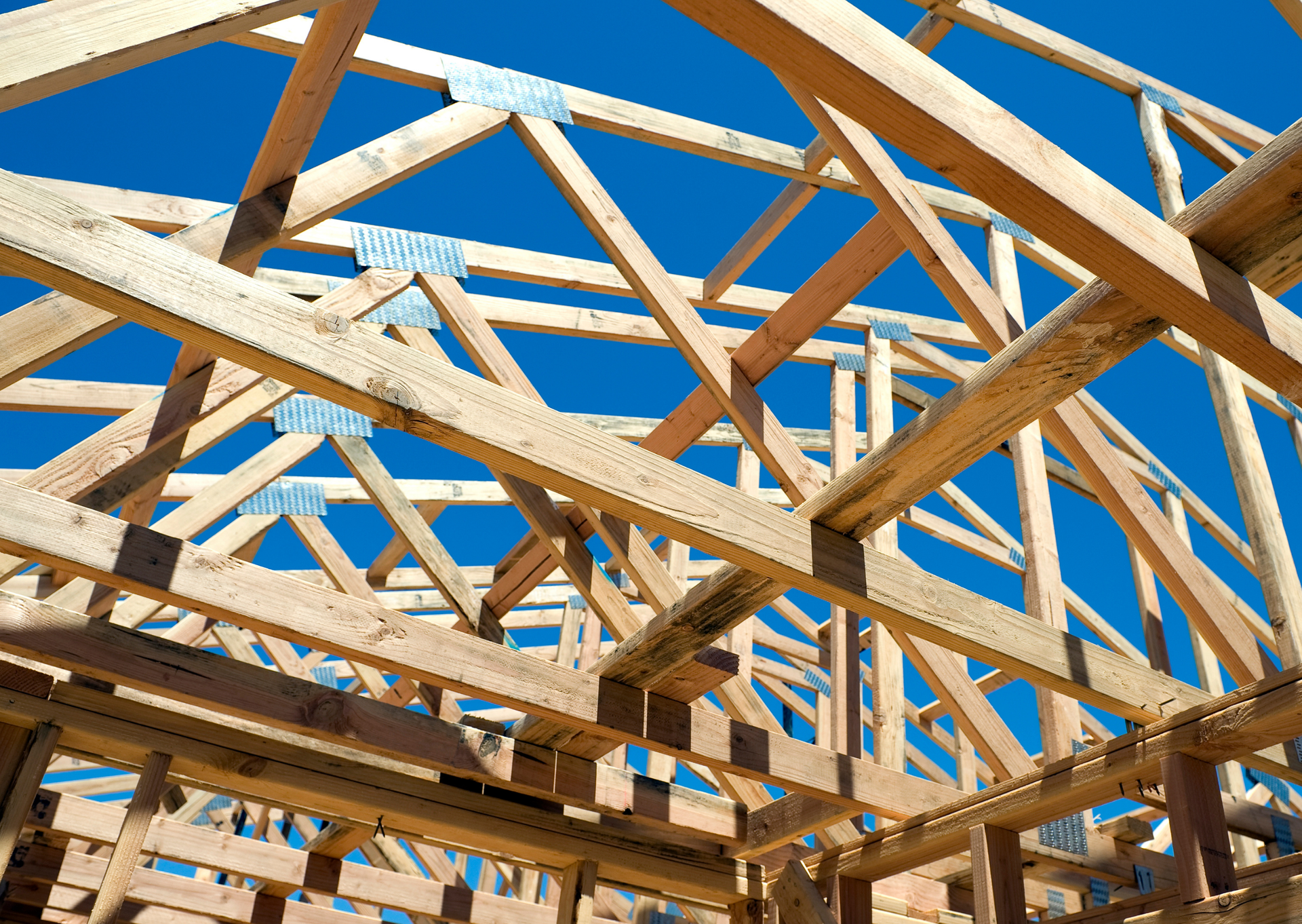 A wooden structure is being built with a blue sky in the background.