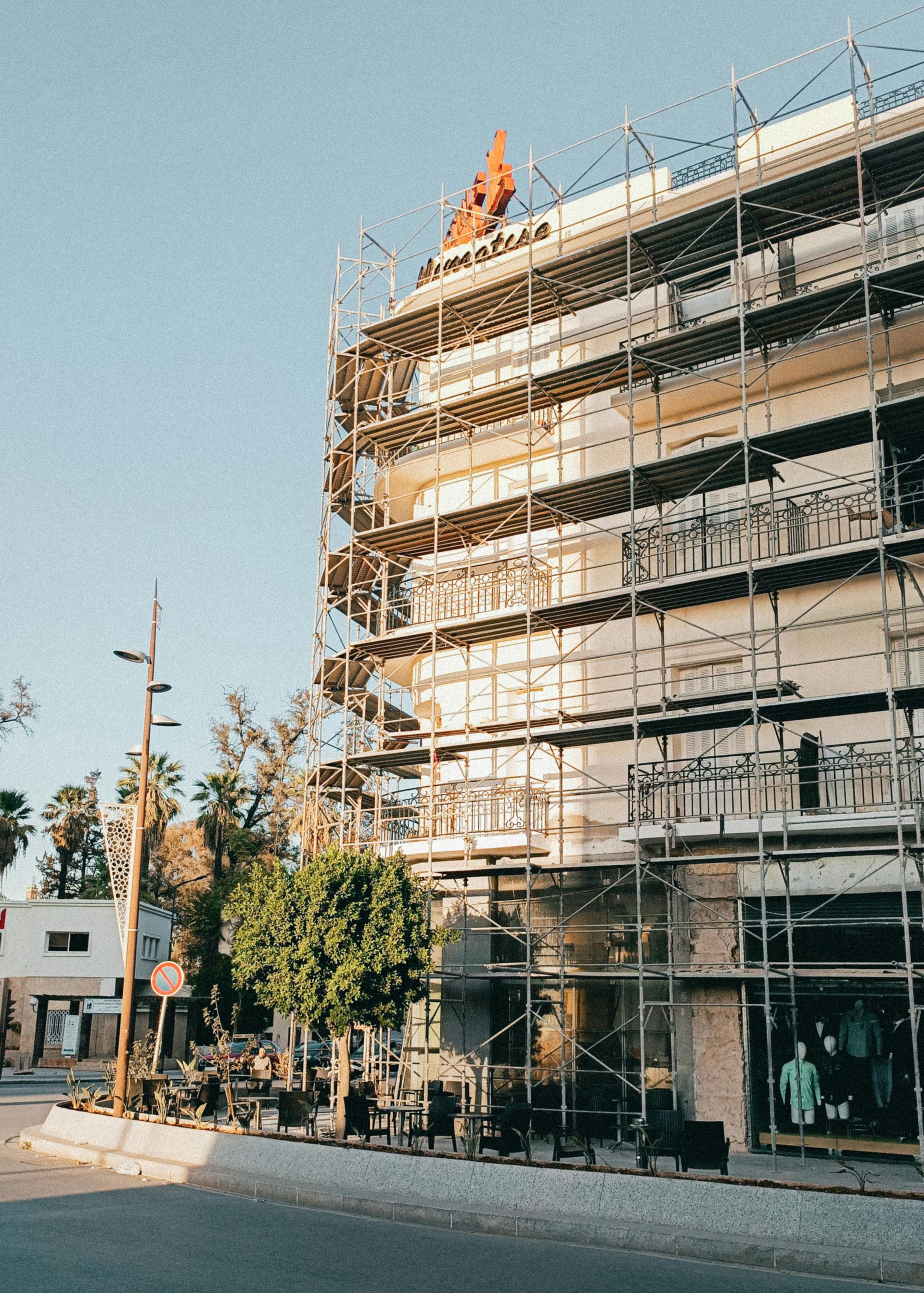 Building facade under construction, scaffolding wraps around the structure, clear sky above.