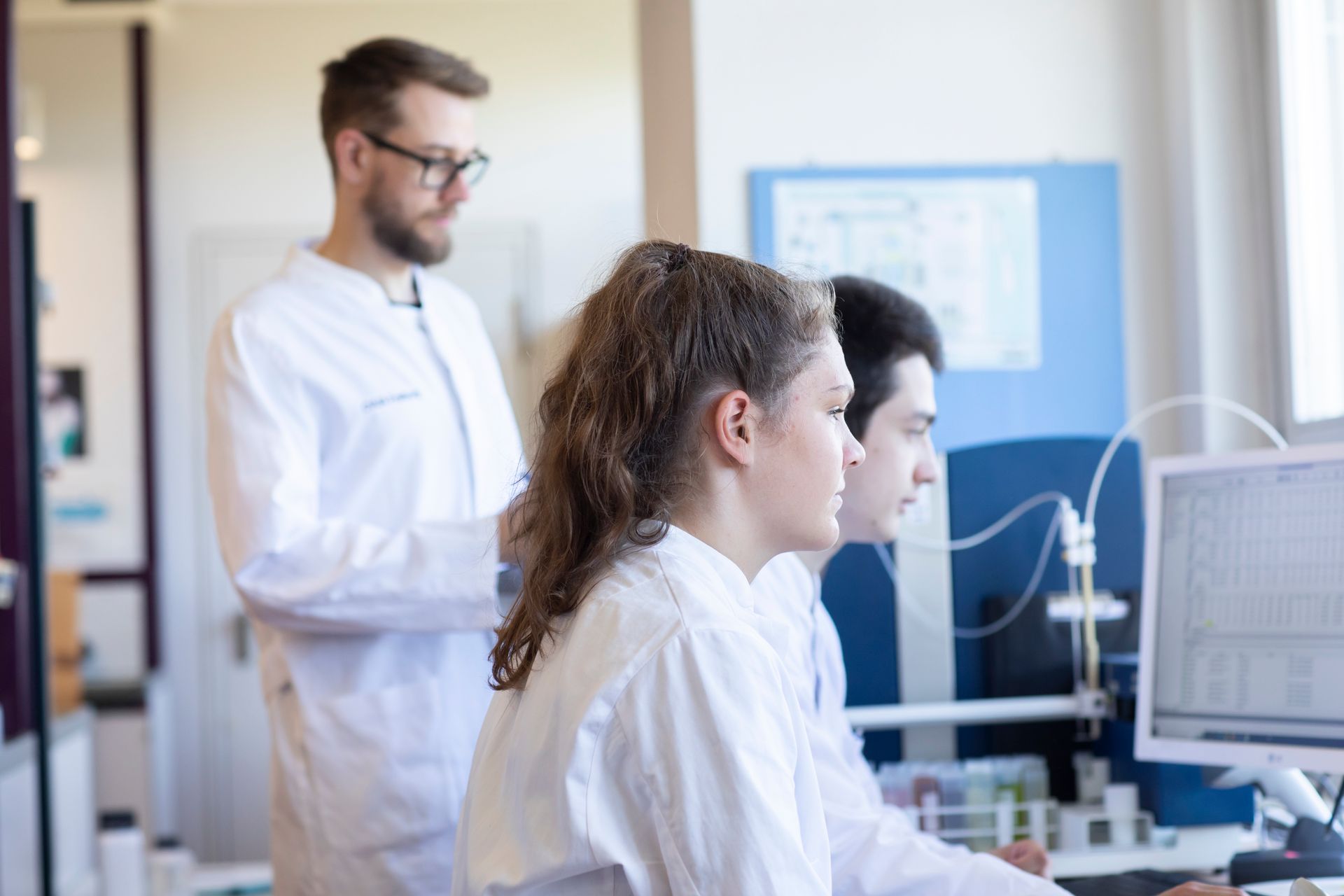 Drei Chemielaboranten werten Laborergebnisse am Computer aus