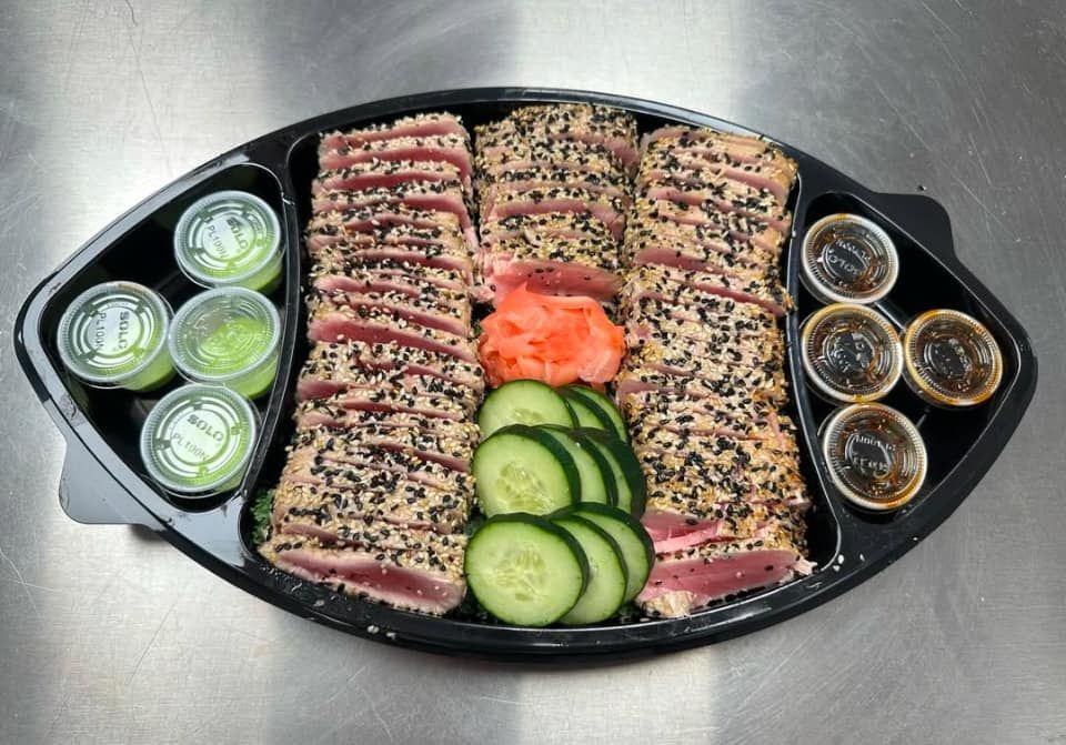 Seared tuna platter with sesame seeds, cucumber, pickled ginger, dipping sauces, and wasabi.