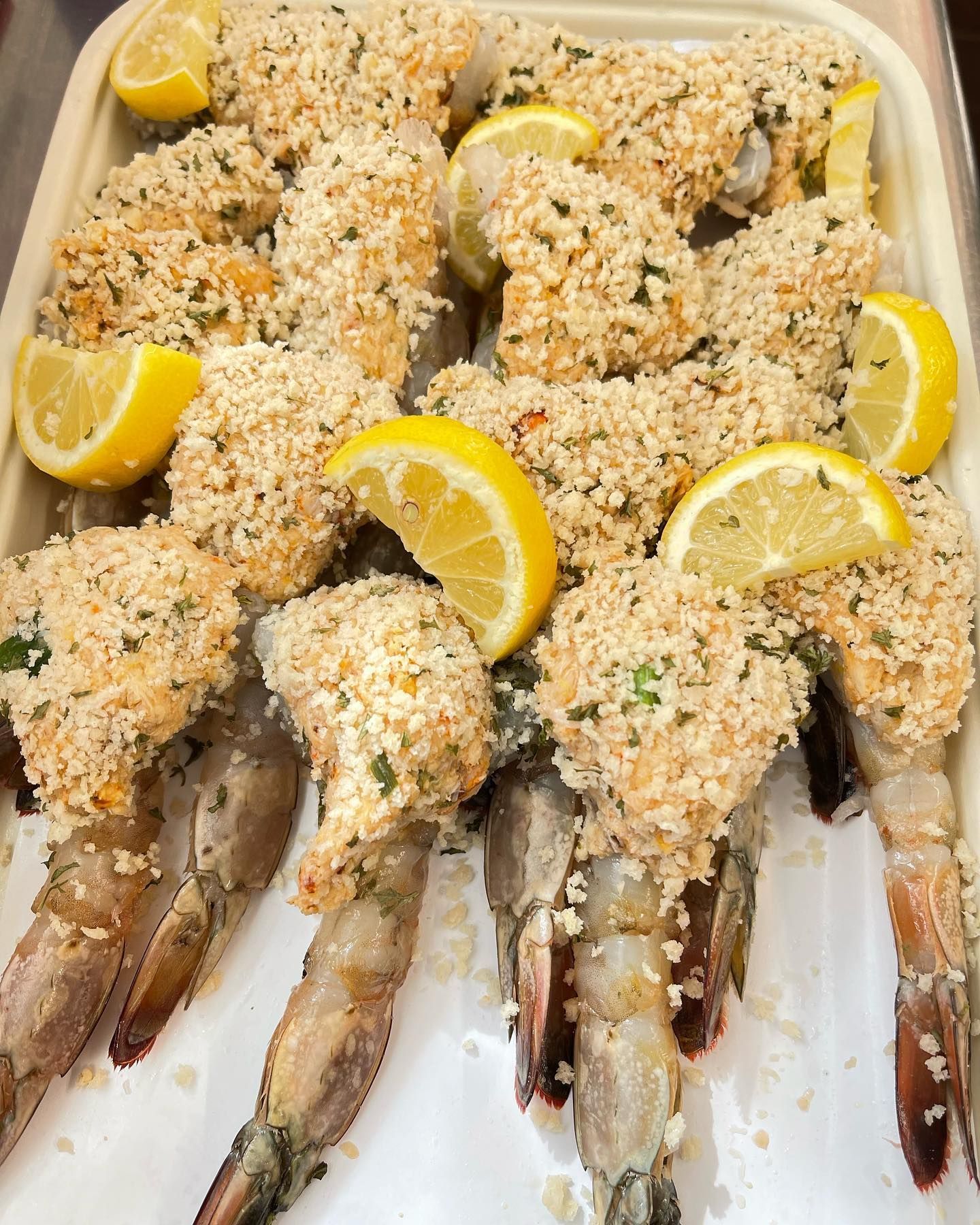 Tray of breaded shrimp with lemon wedges.