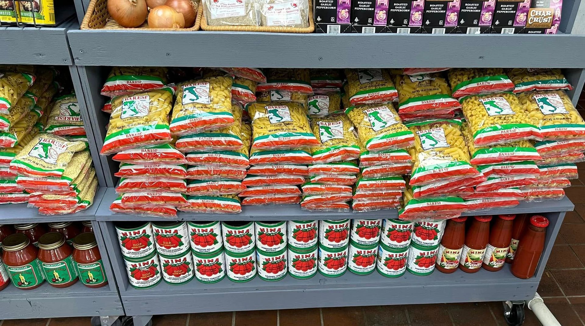 Shelves stocked with pasta and tomato products at a grocery store.
