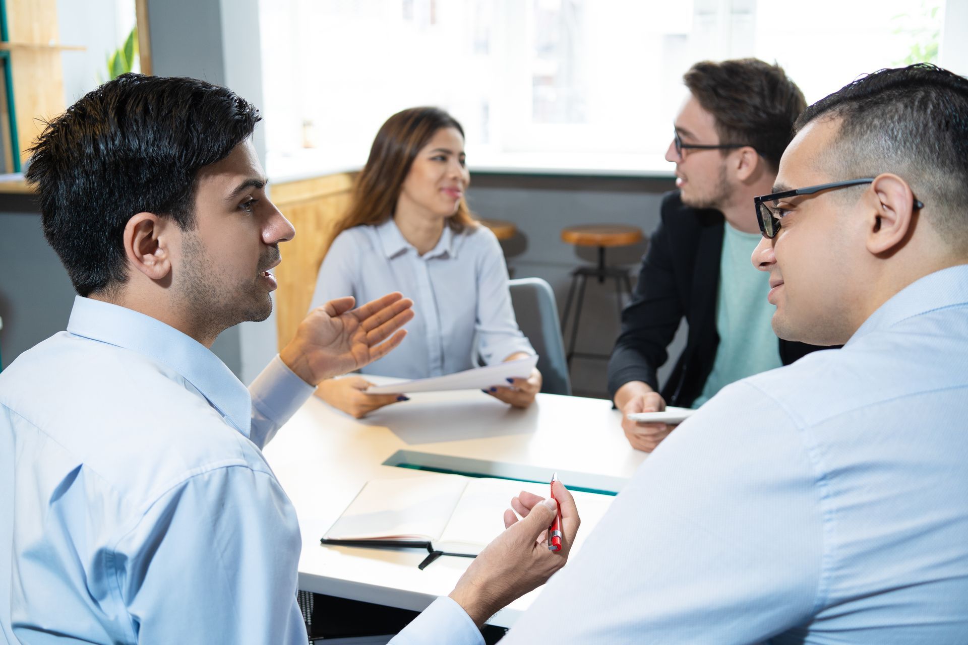 A group of people are sitting around a table having a meeting.