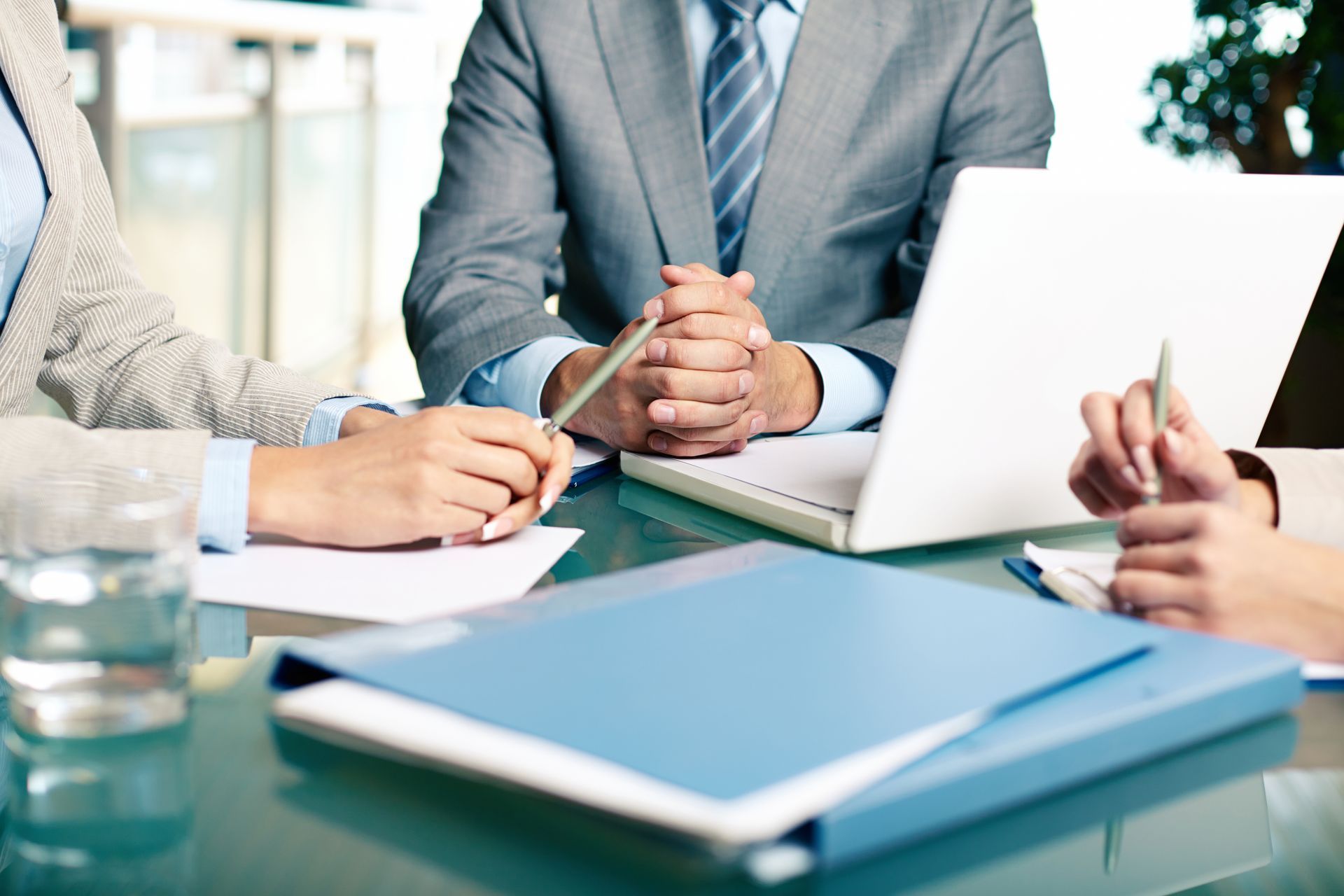 A group of people are sitting at a table with papers and a laptop.