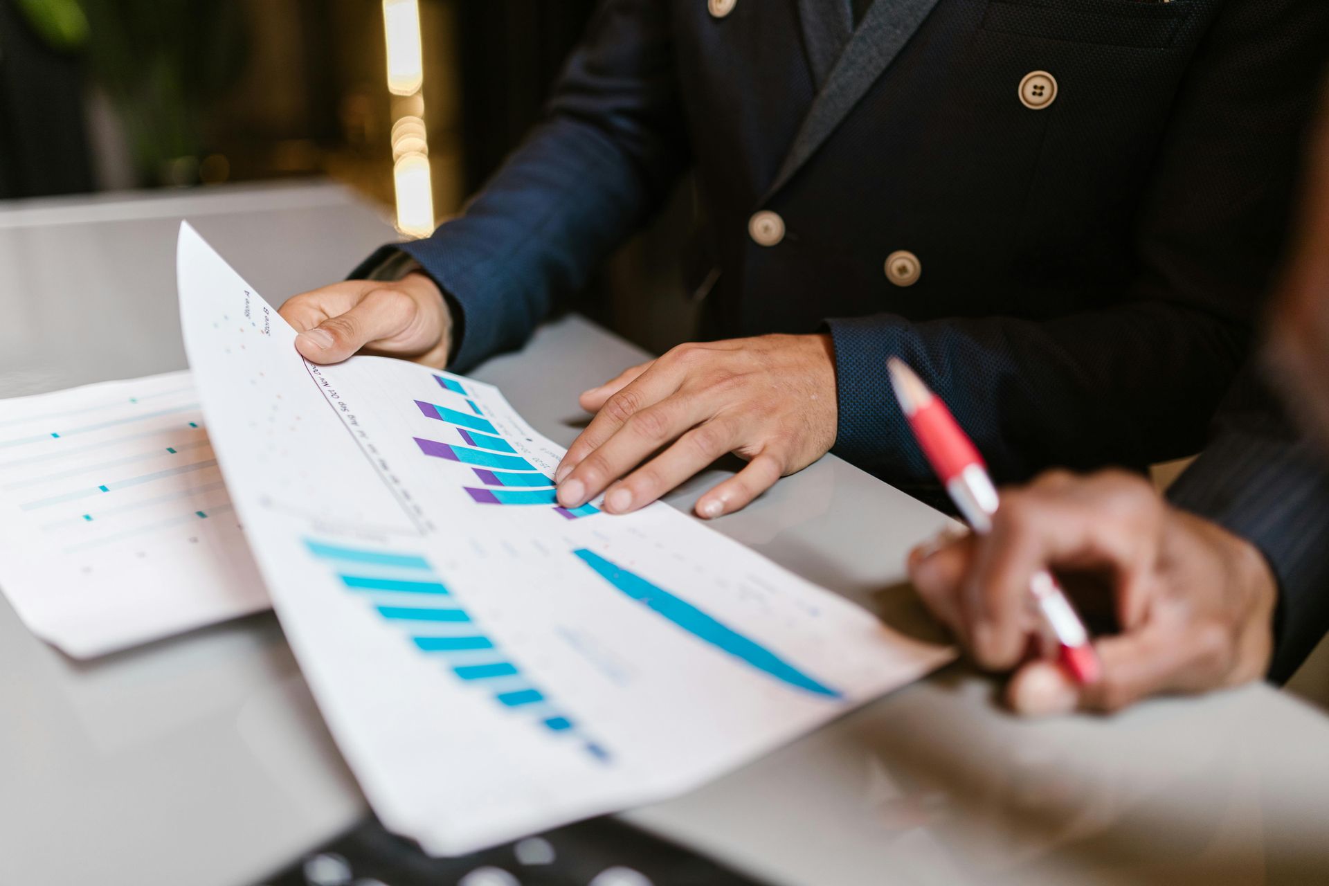 Two people sitting at a table with papers and charts, discussing finances and business goals