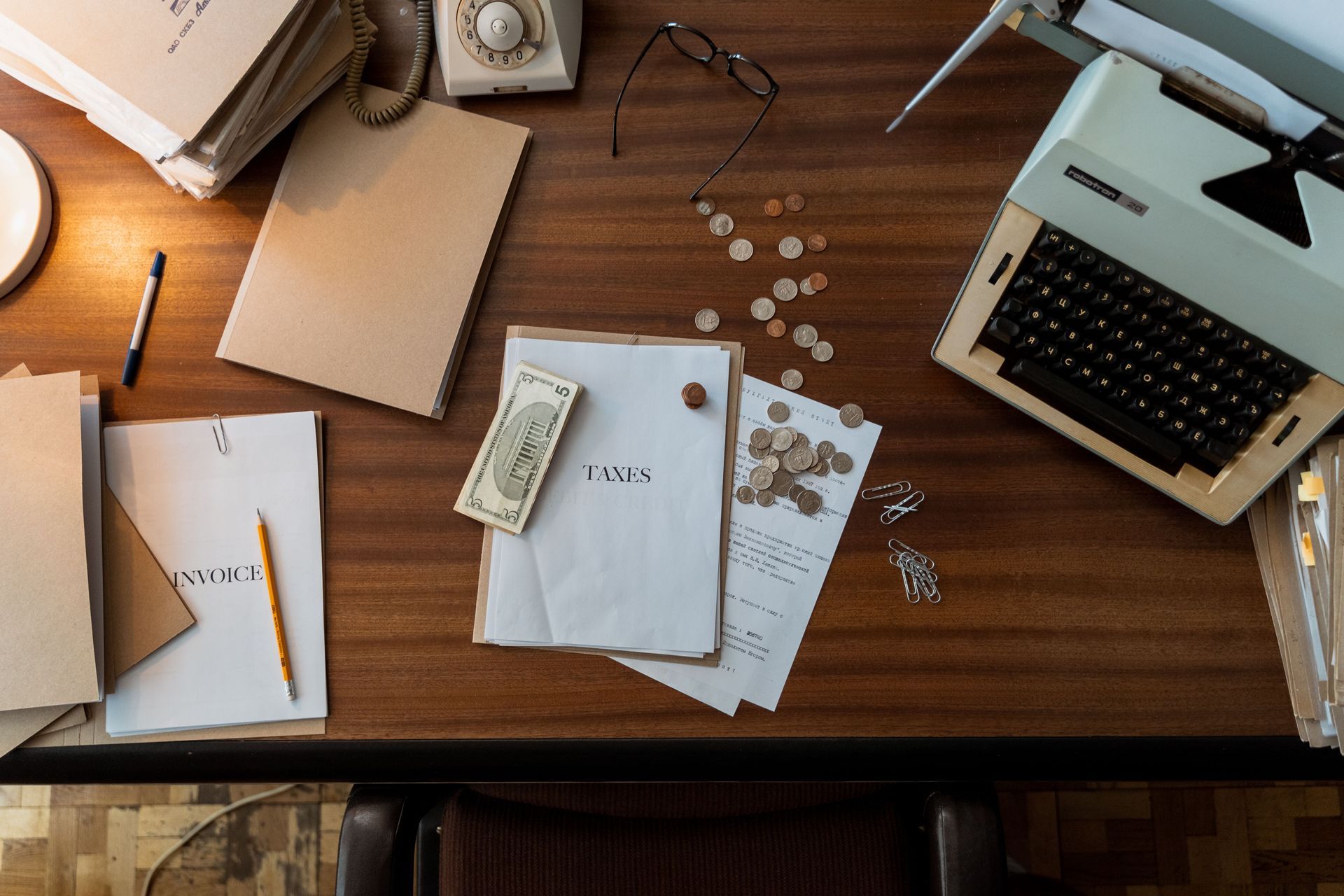 Photo of wooden table with documents, folders, and money laid out