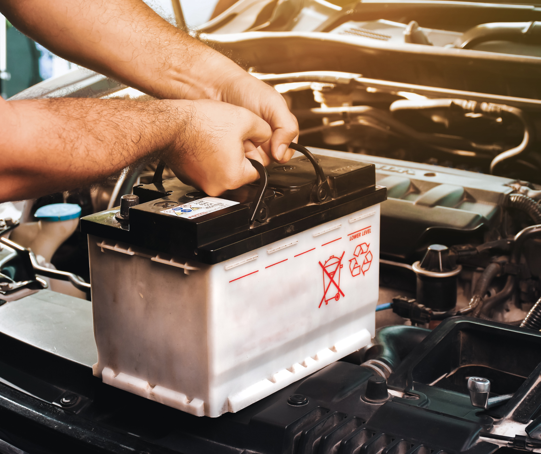 Person installing a car battery in an engine bay.