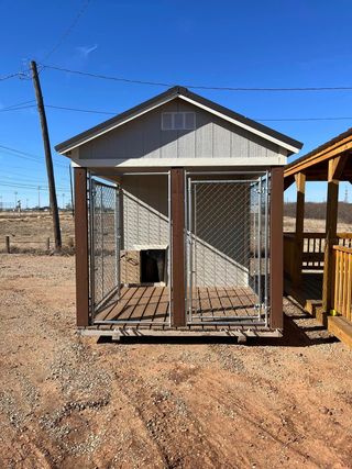 A small dog kennel is sitting in the middle of a dirt field.