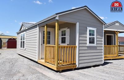 A small house with a porch and a garage in the background