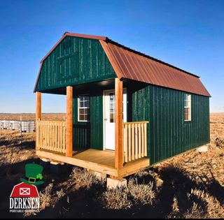 A green barn with a red roof and a porch