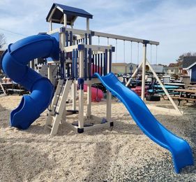 A playground with a blue slide and a blue spiral slide