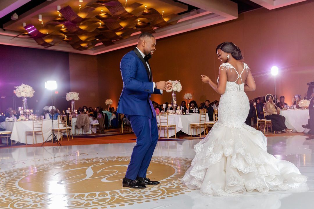 Bride and groom dancing at wedding reception on a round floor. The man in blue suit, woman in white dress.