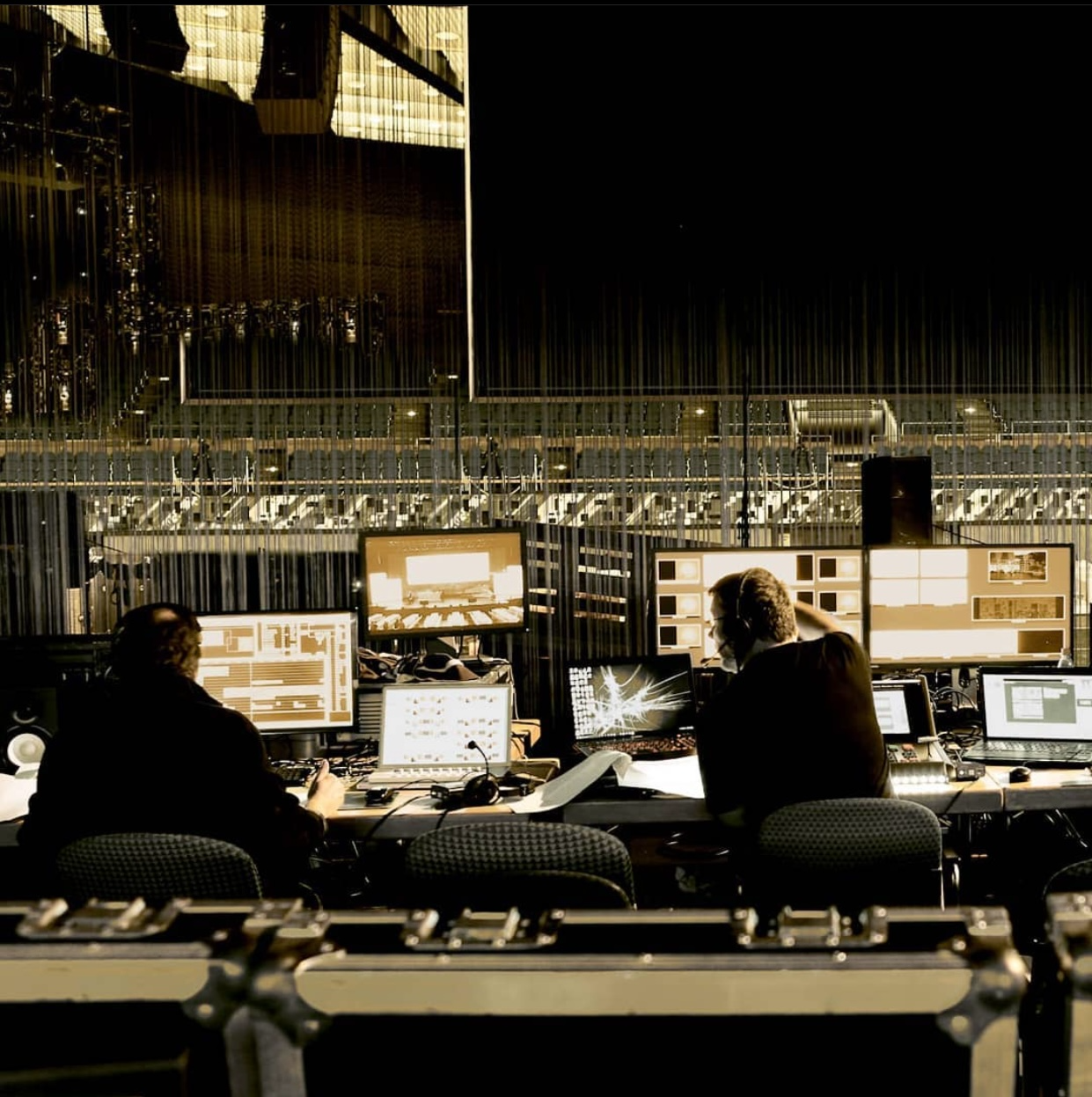 Two people are sitting at desks in front of computer monitors.
