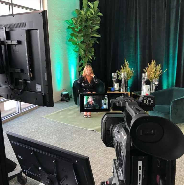 A woman is sitting in front of a camera in a room.