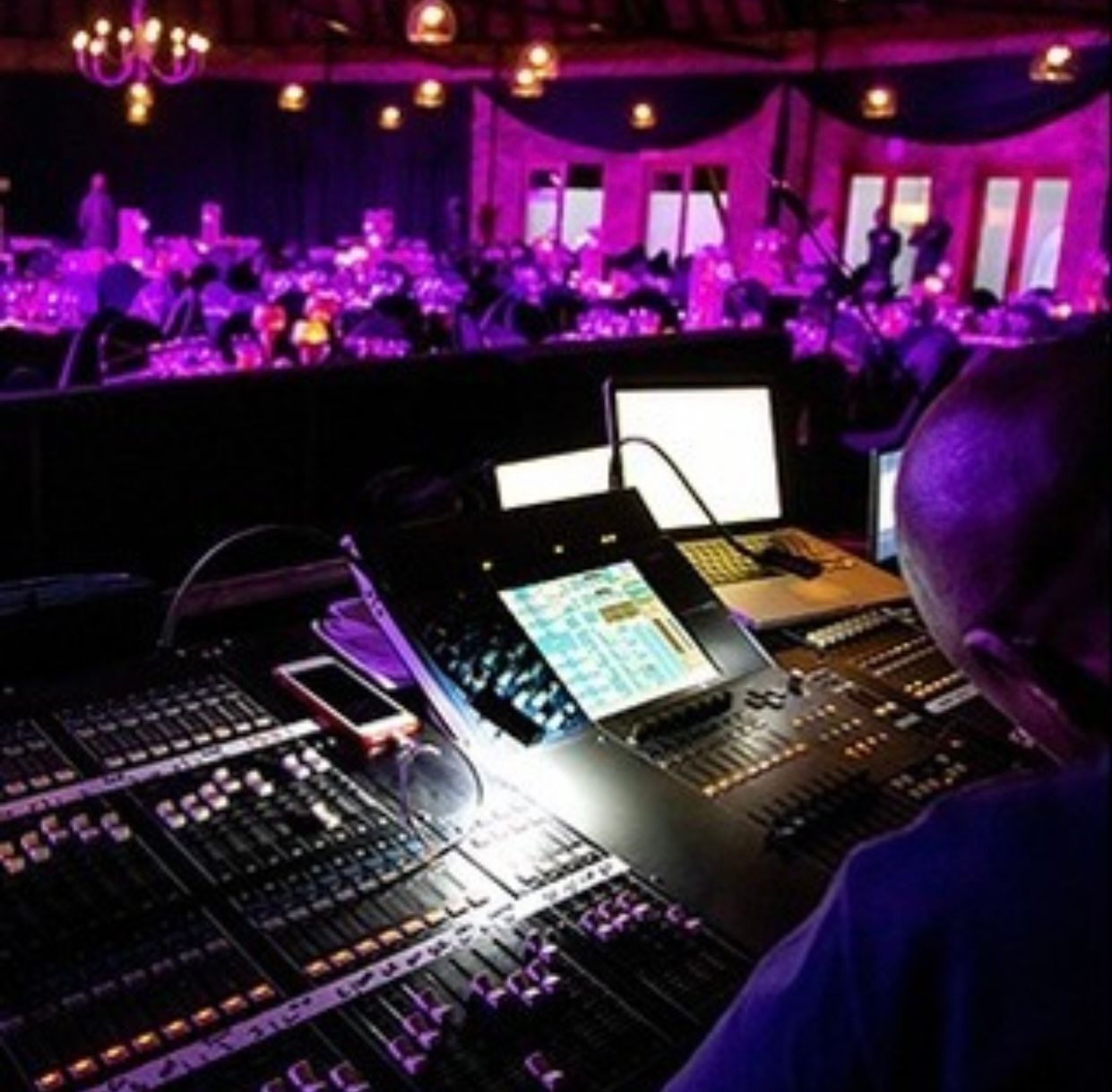 A man sitting in front of a mixer in a dark room.