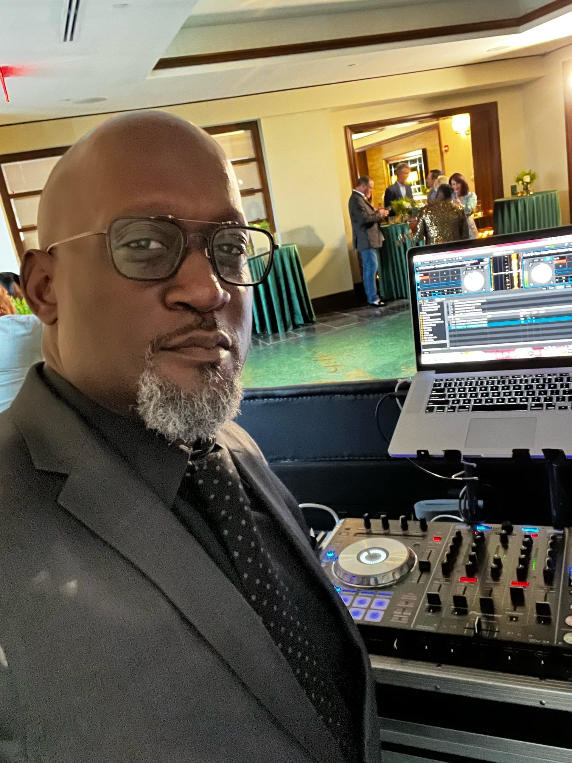 A man in a suit and tie is standing in front of a laptop.