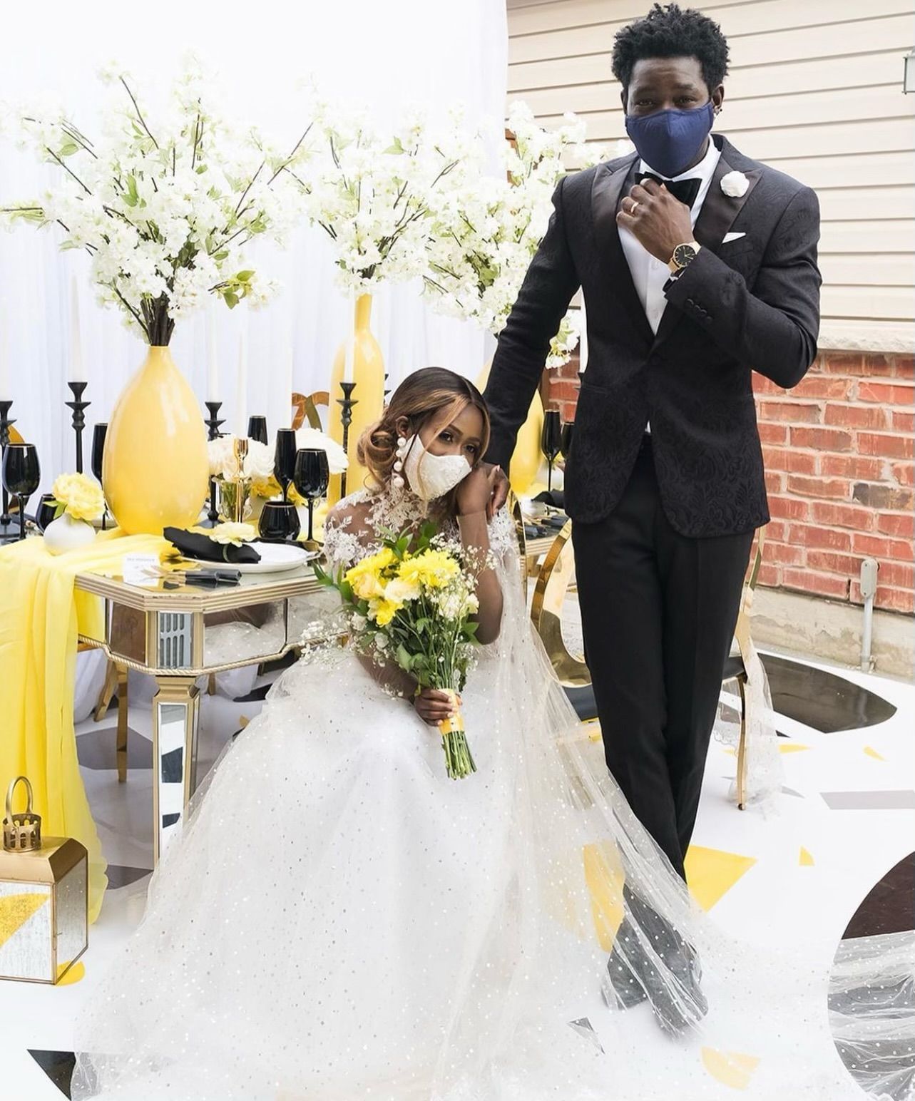 A bride and groom wearing face masks are standing next to each other.