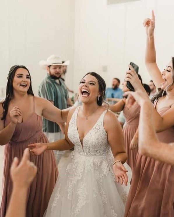 A bride and her bridesmaids are dancing at a wedding reception.