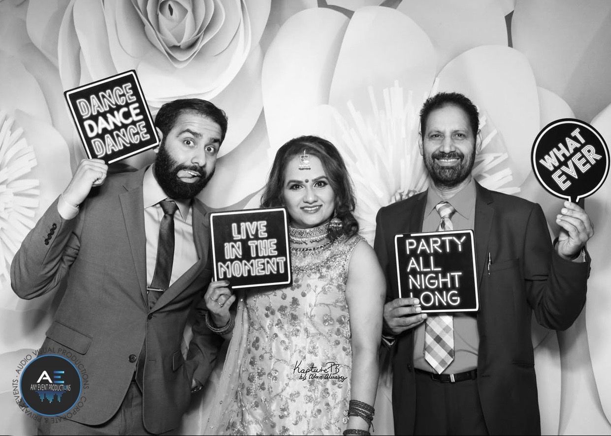 A group of people are posing for a picture in a photo booth while holding signs.