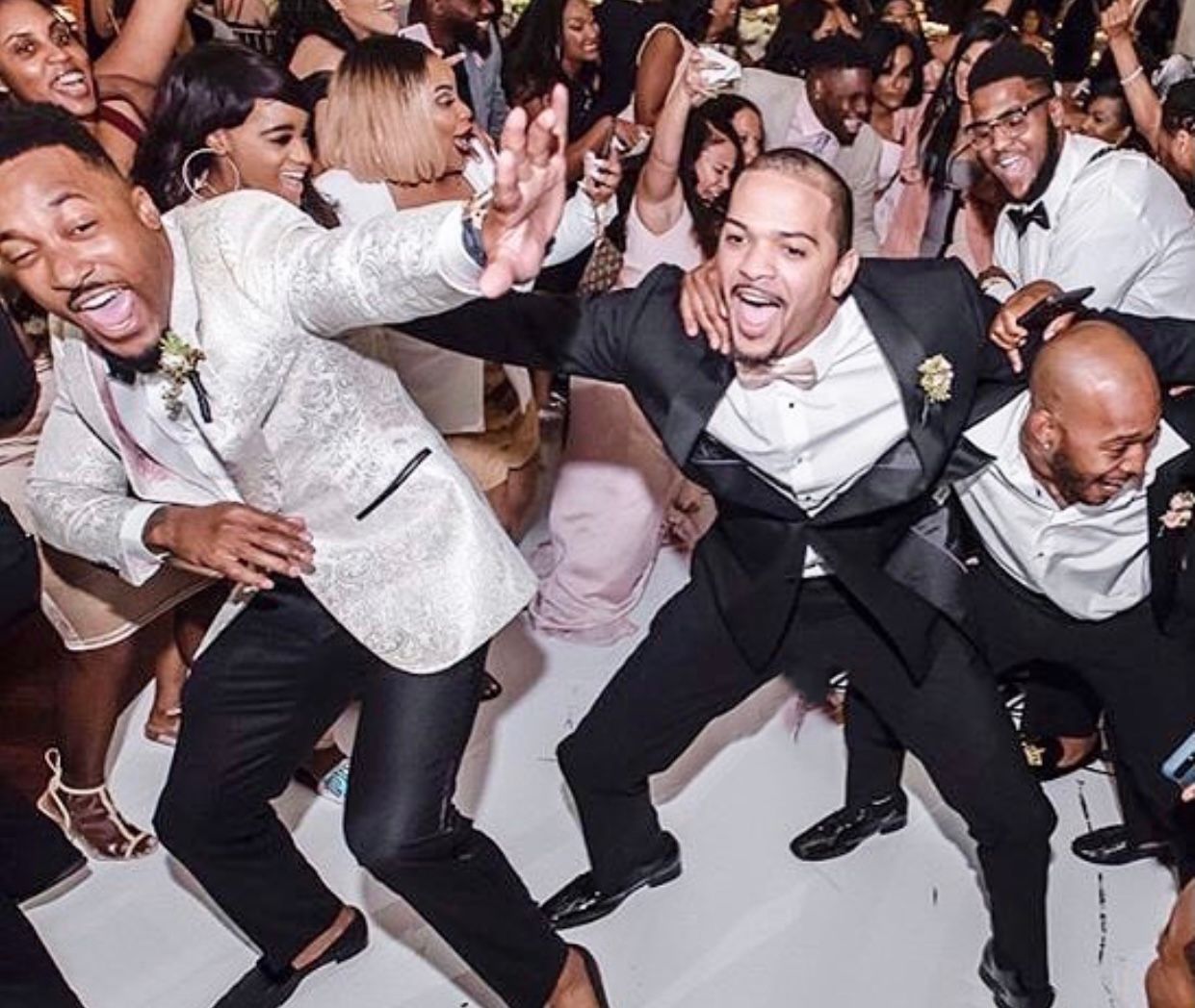 A group of men in tuxedos are dancing in front of a crowd.
