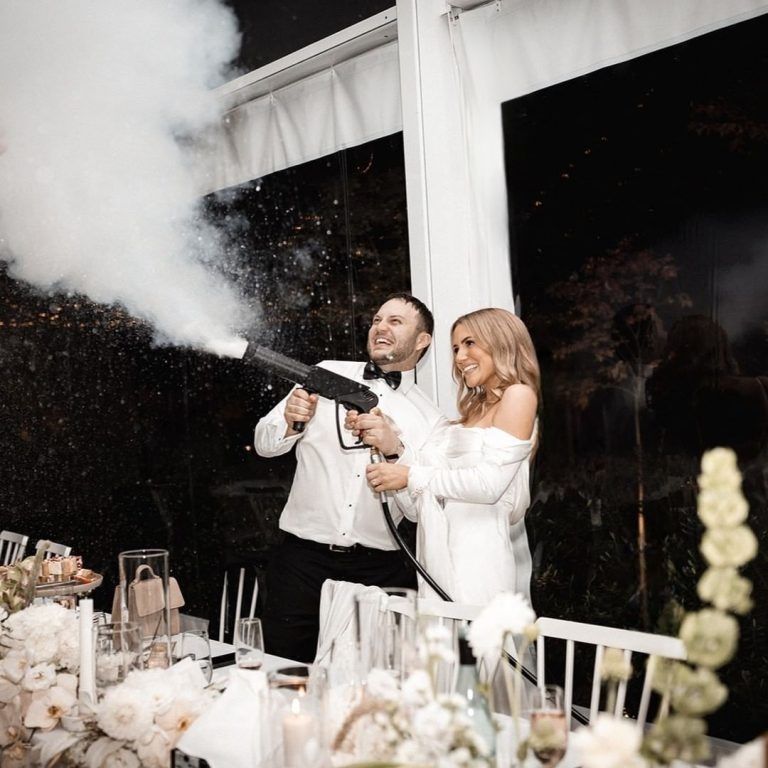 A bride and groom are popping confetti in a reception.