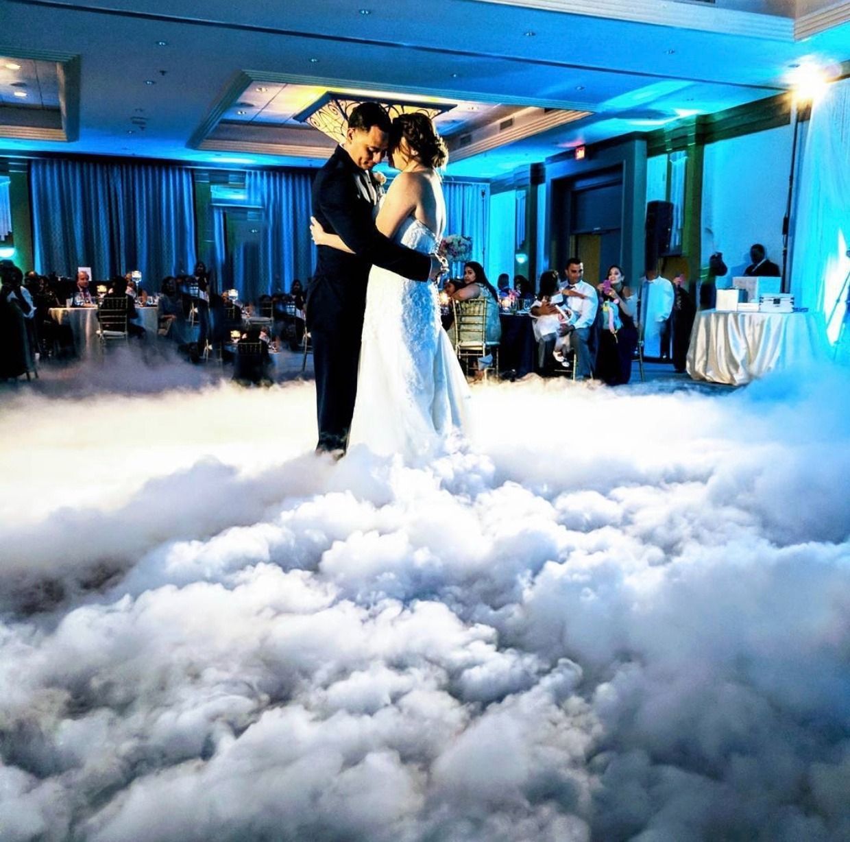 A bride and groom are dancing on a cloudy floor.