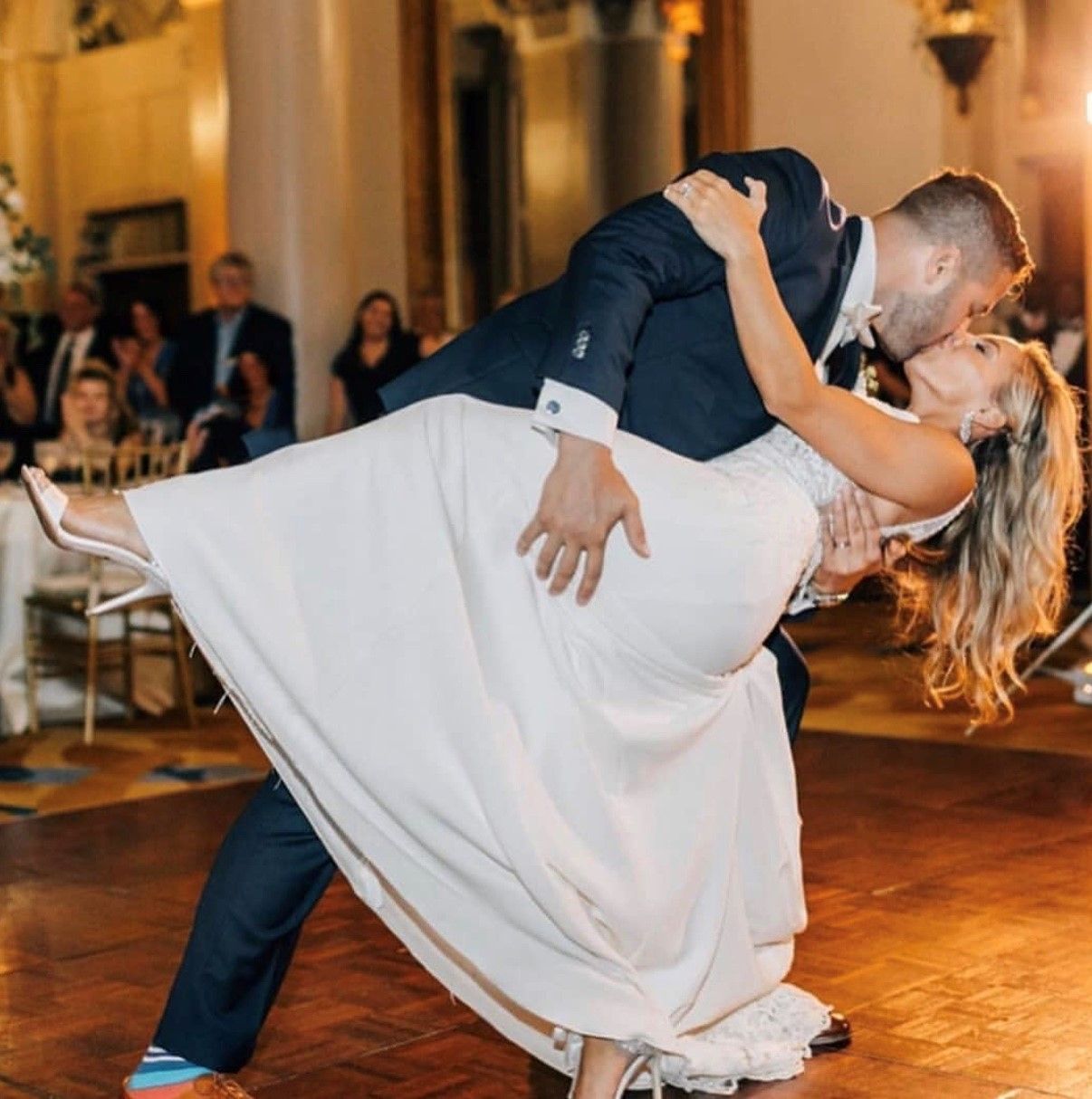 A bride and groom are kissing during their first dance.
