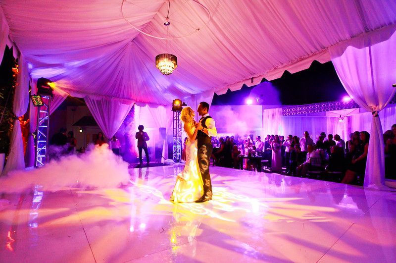 A bride and groom are dancing under a tent at a wedding reception.
