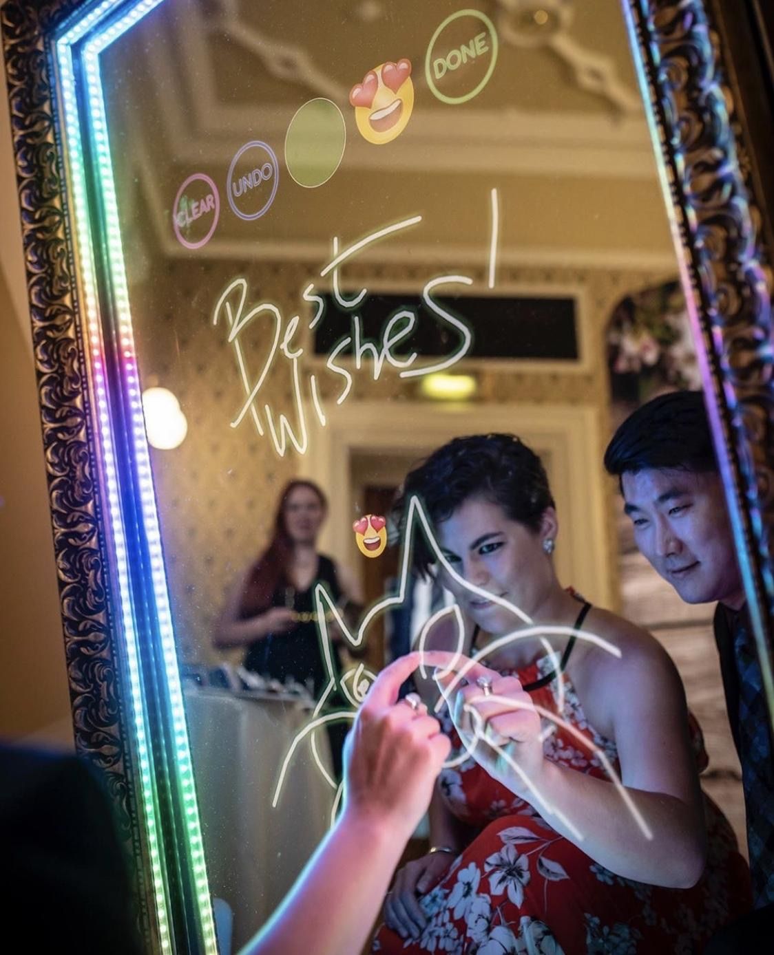 A woman is writing on a mirror that says best wishes.