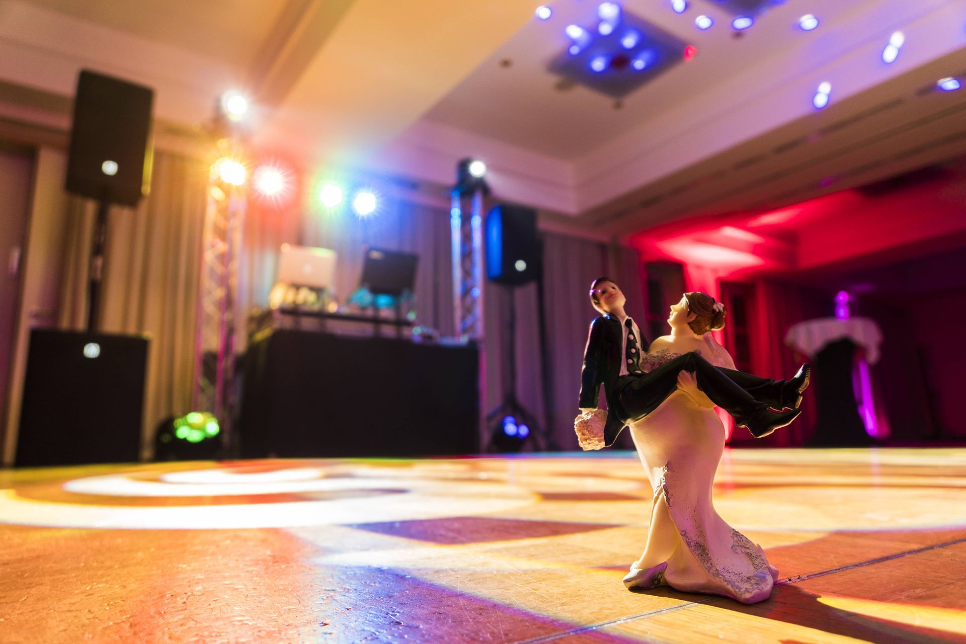 A bride and groom figurine are dancing on a dance floor.