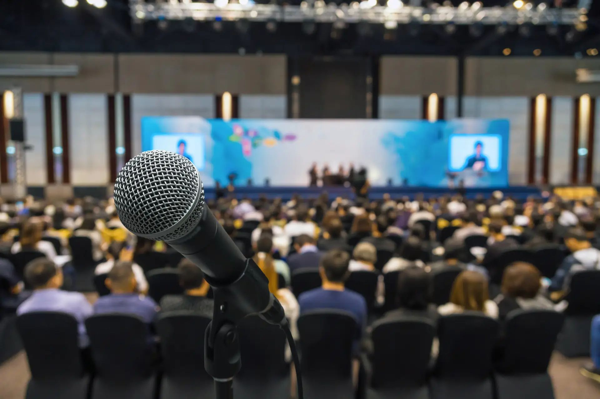A microphone is sitting in front of a crowd of people in an auditorium.