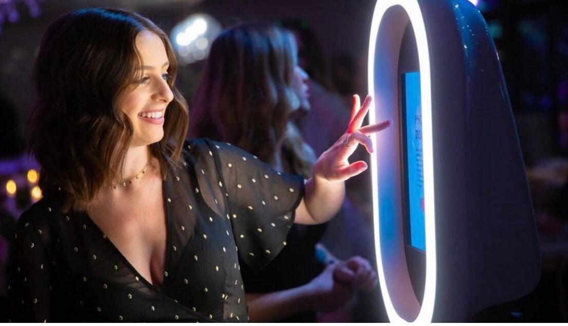 A woman is taking a picture of herself in a photo booth.