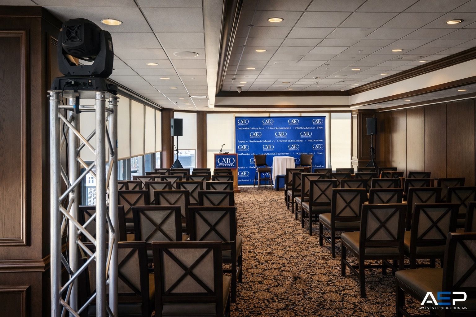 Empty conference room with rows of chairs facing a blue AP-branded backdrop and podium.
