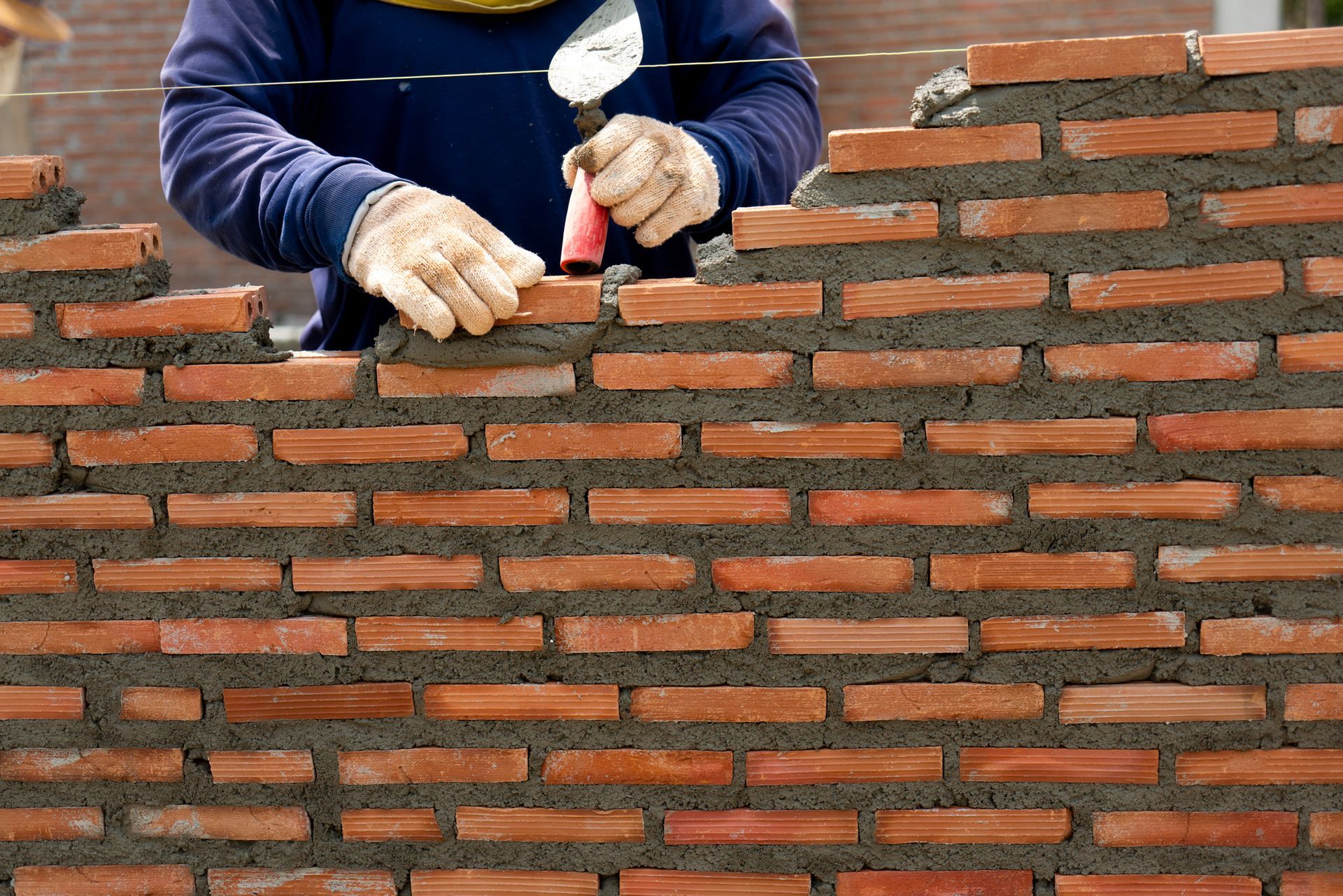 A man is laying bricks on a brick wall.