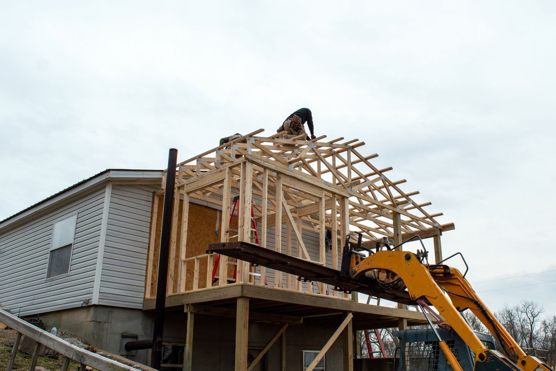 A man is standing on top of a house under construction. A man is standing on top of a house under construction.