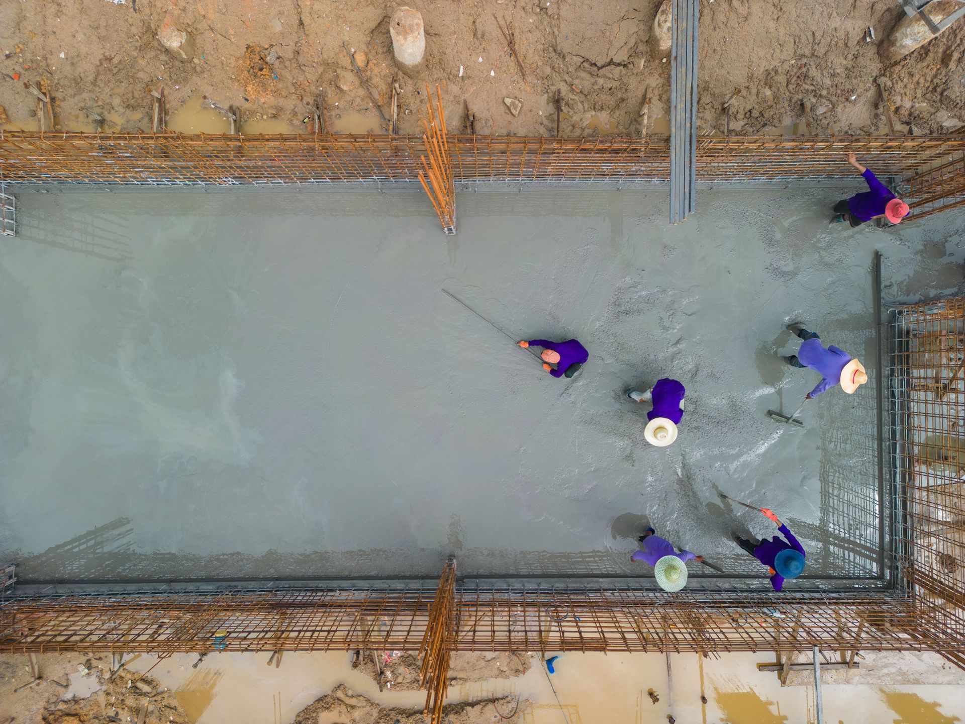 An aerial view of a group of construction workers working on a concrete floor.