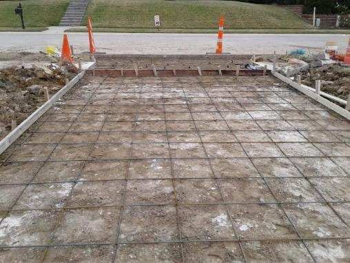 A concrete driveway is being built in front of a house.
