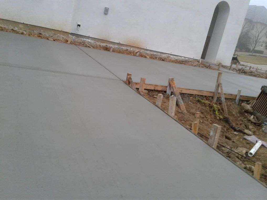 A concrete driveway is being built in front of a white building