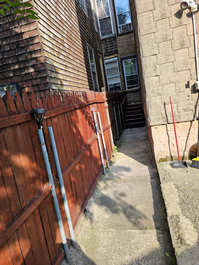 A wooden fence surrounds a sidewalk leading to a building.