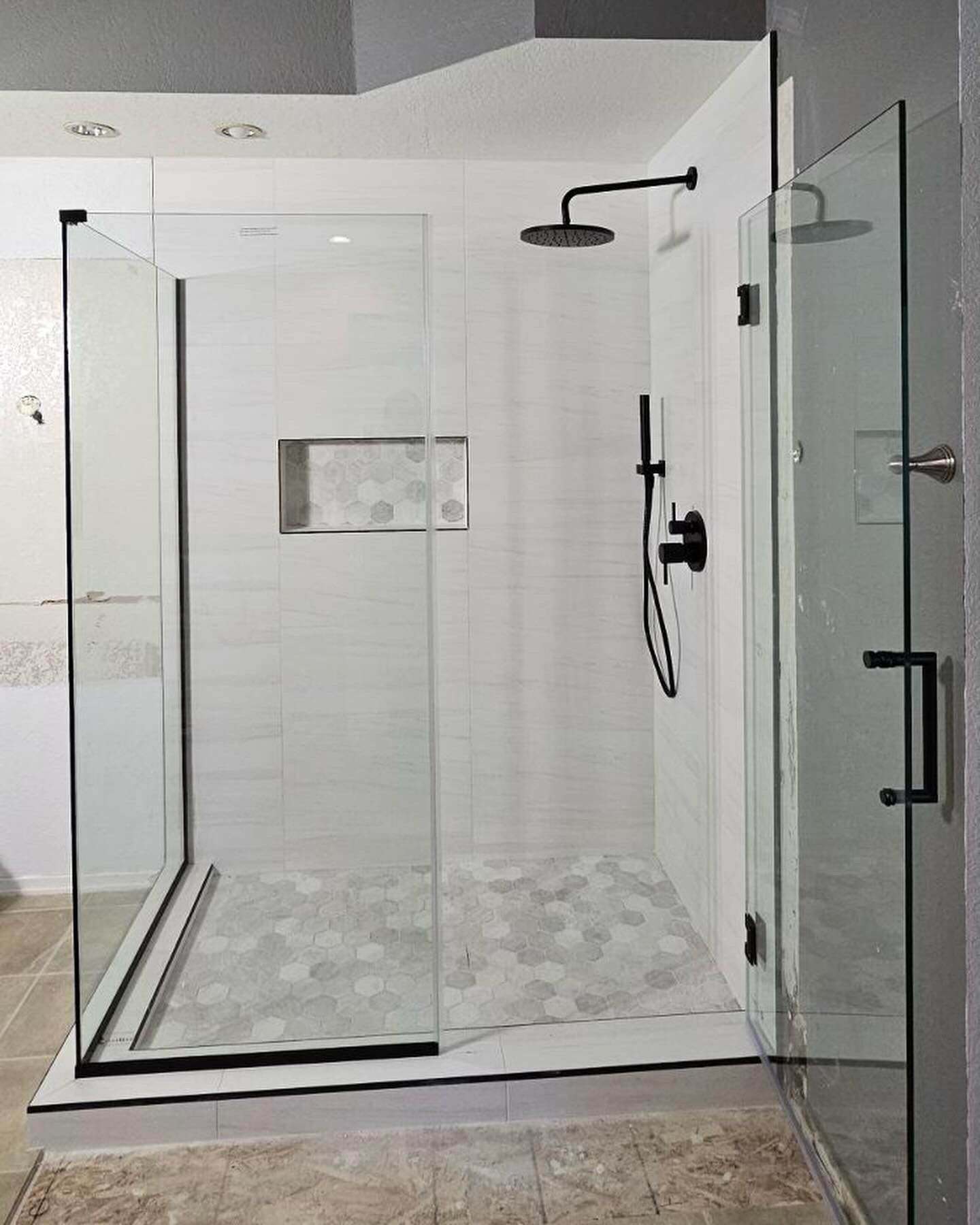 A bathroom with a walk in shower with a black shower head.