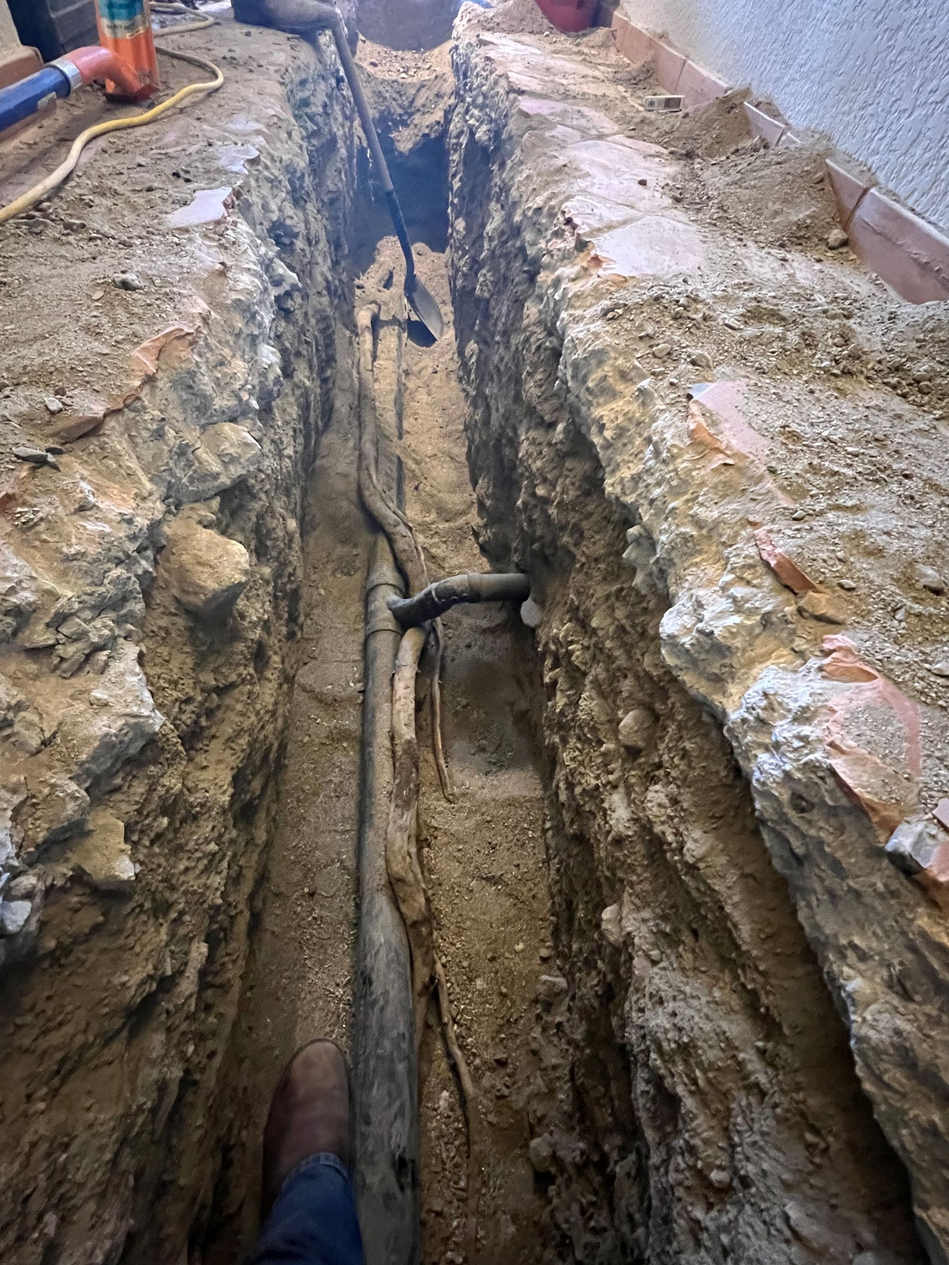A person is digging a hole in the ground to install a pipe.