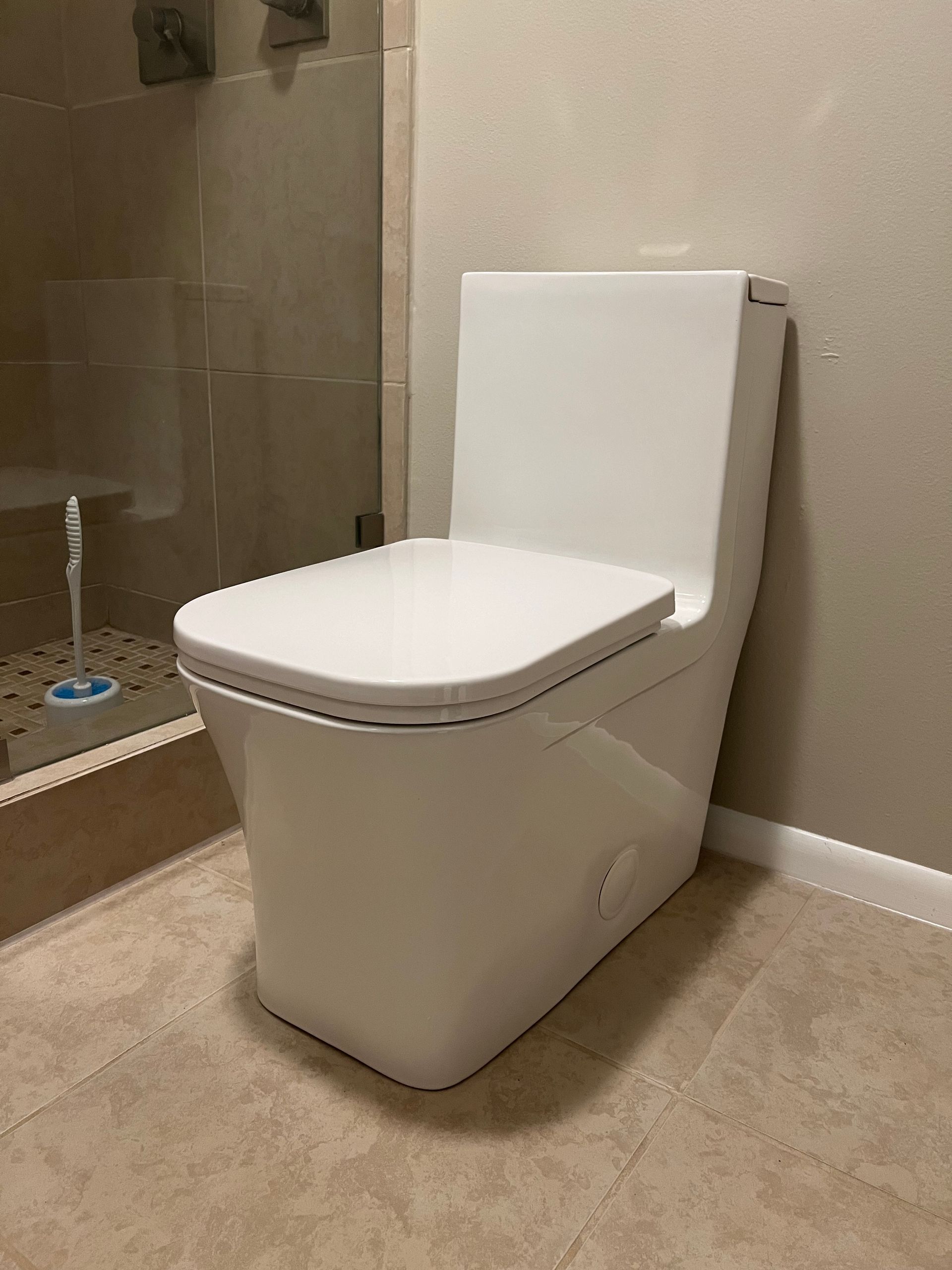 A white toilet is sitting in a bathroom next to a shower.