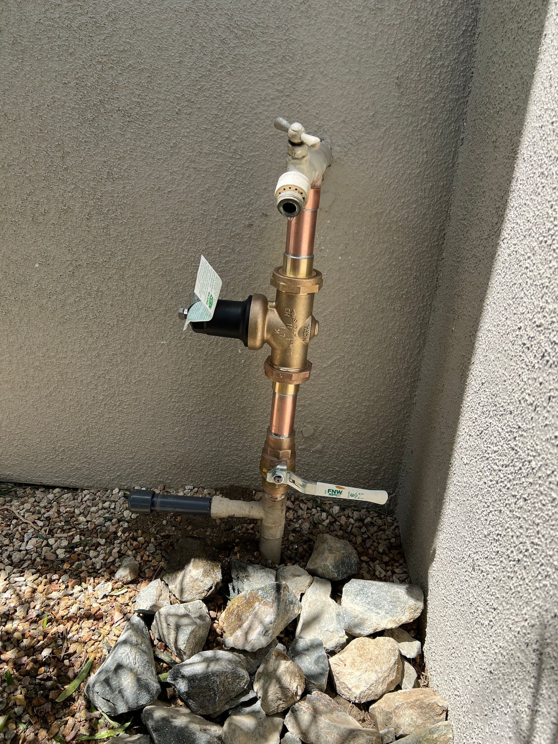 A faucet is sitting on top of a pile of rocks next to a wall.