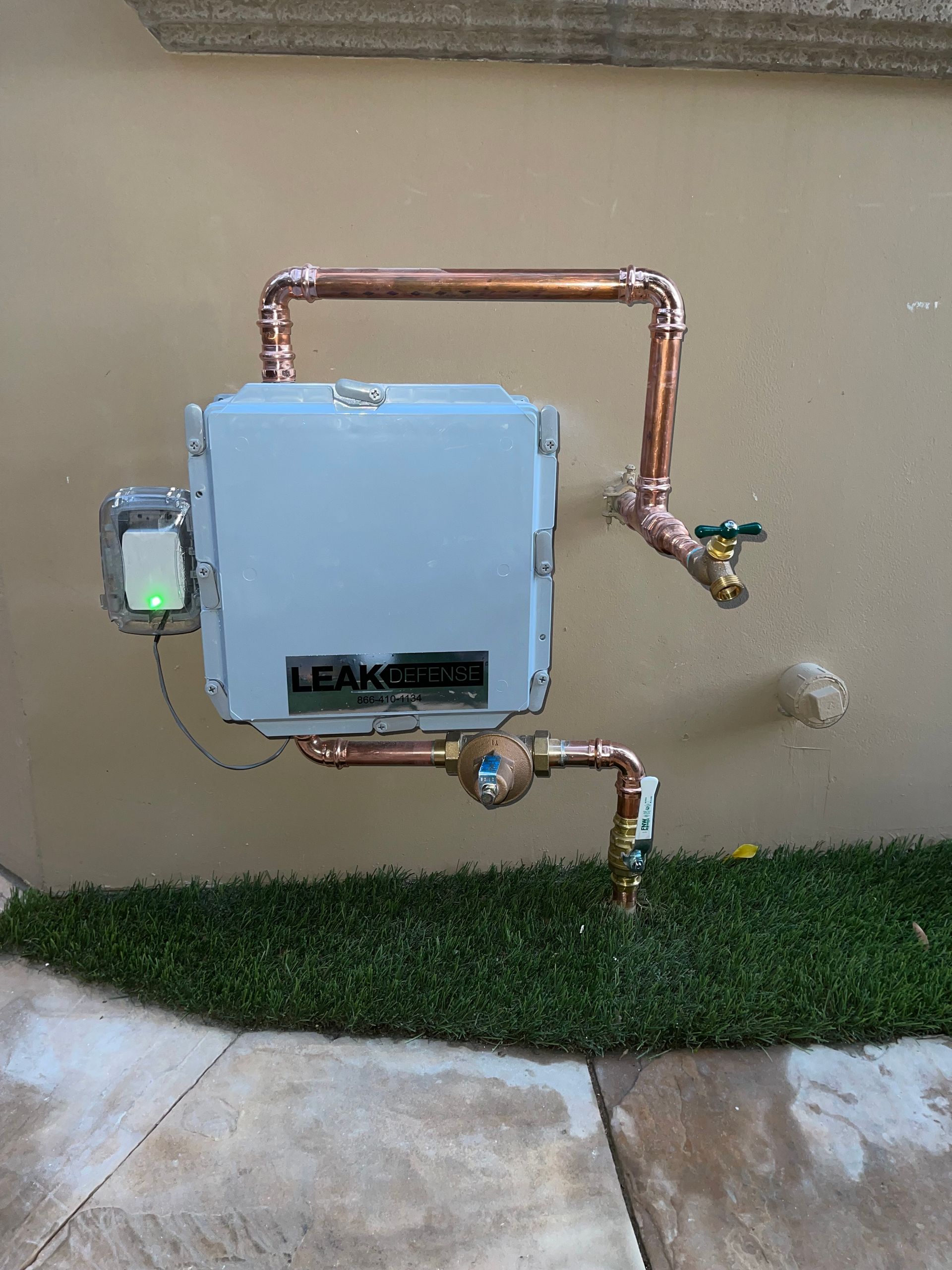 A white box with copper pipes attached to a wall.