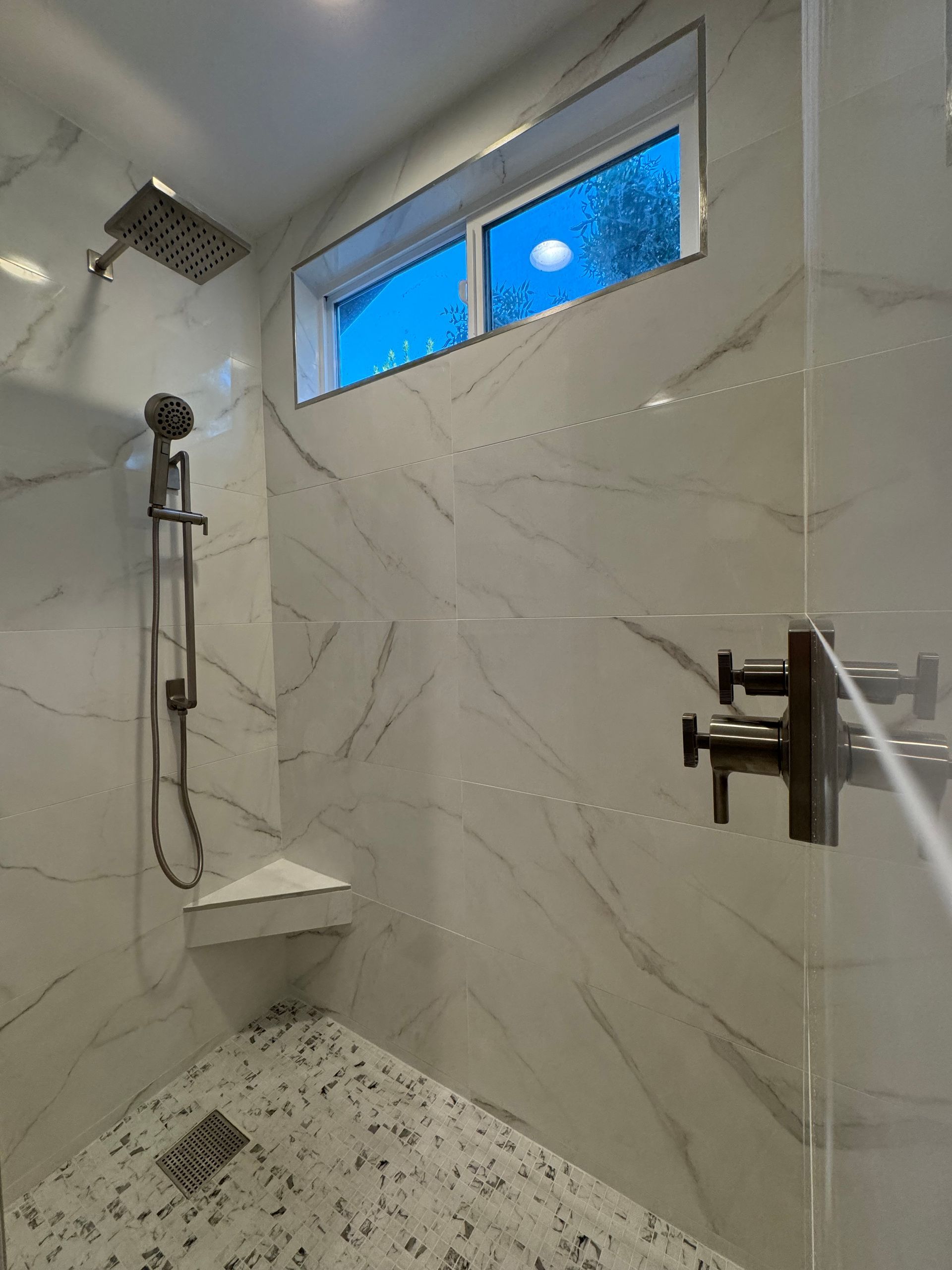 A bathroom with a walk in shower and a window.