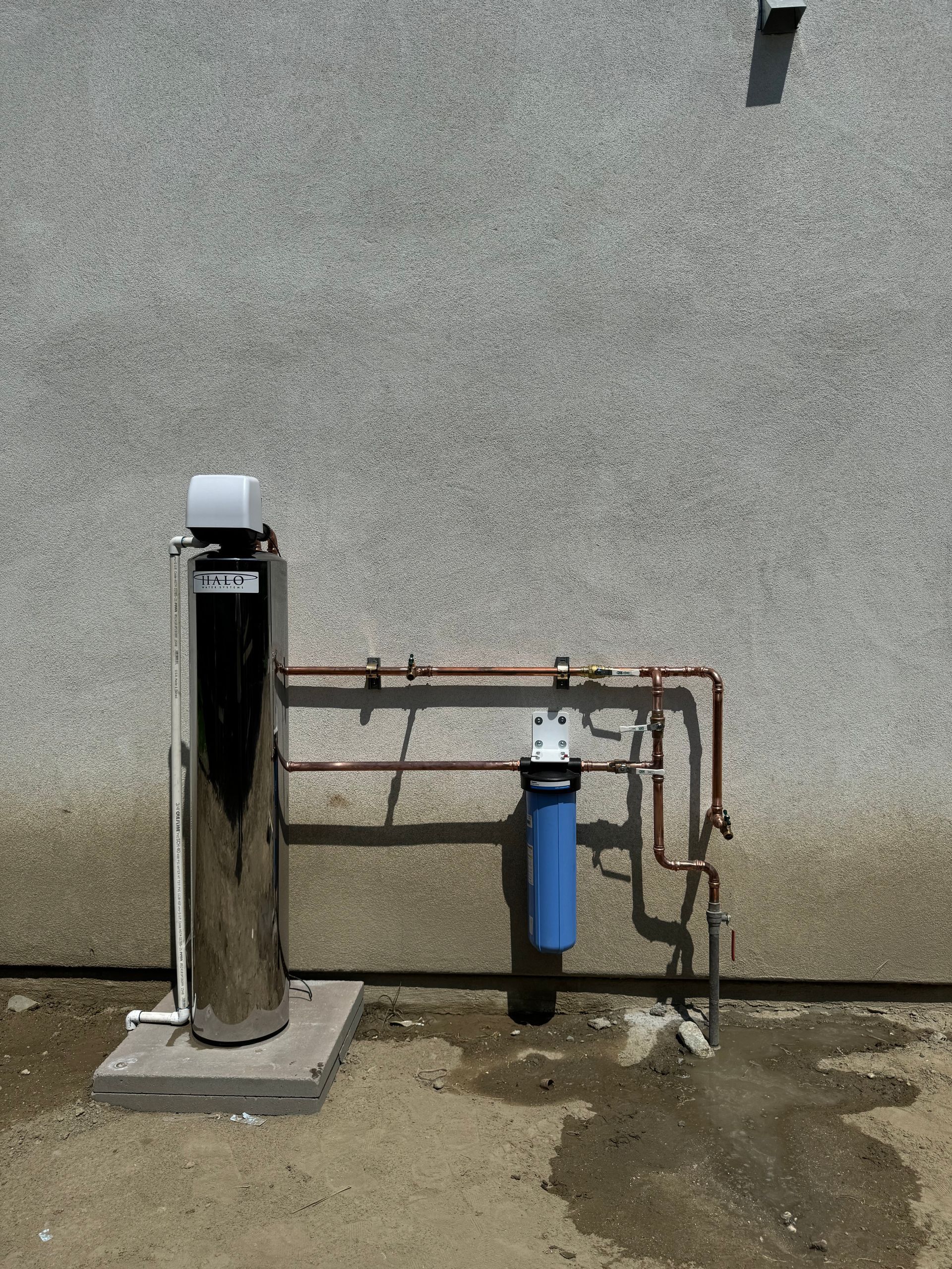 A water filter is sitting on the ground next to a wall.