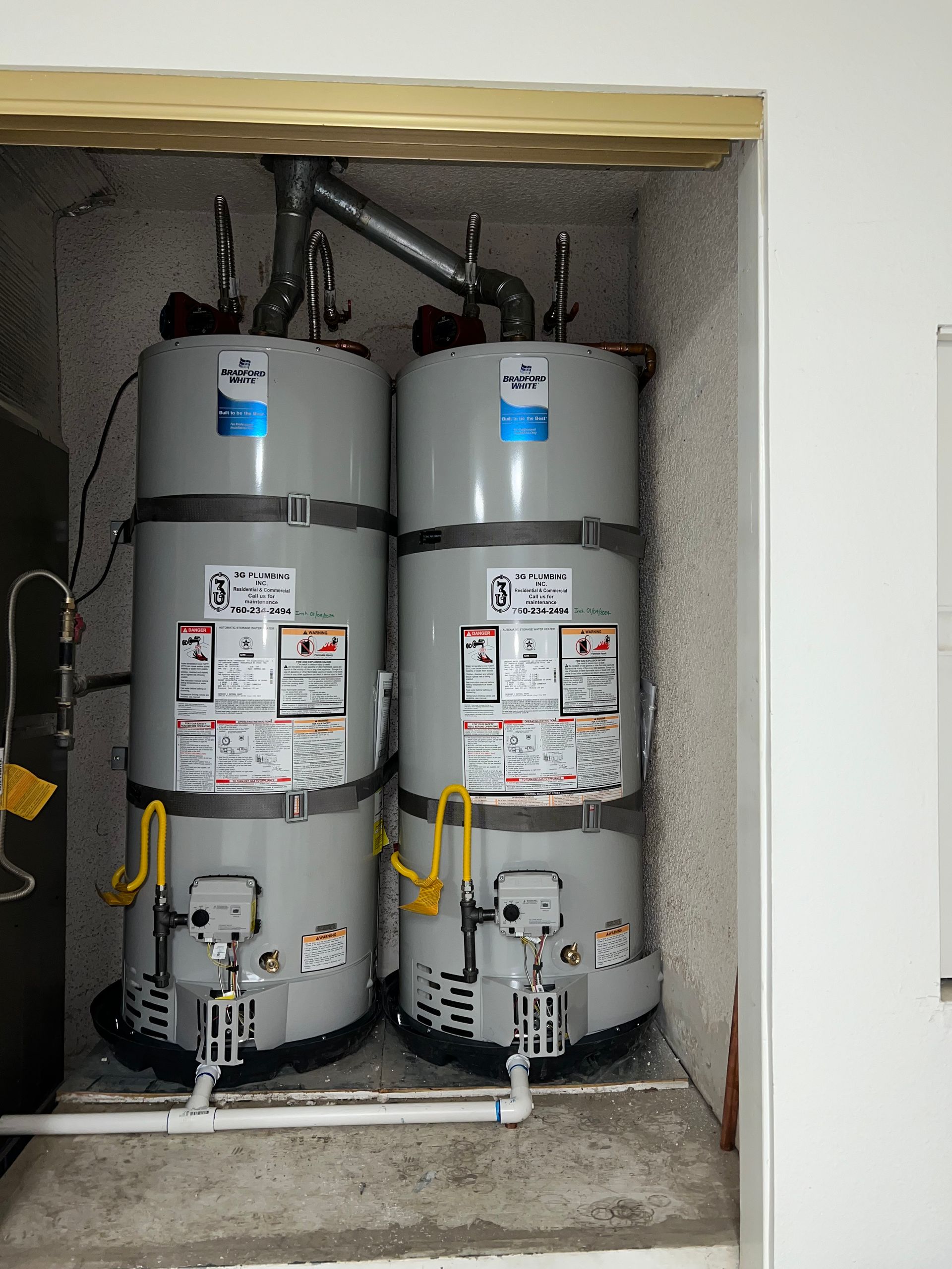 Two water heaters are stacked on top of each other in a room.