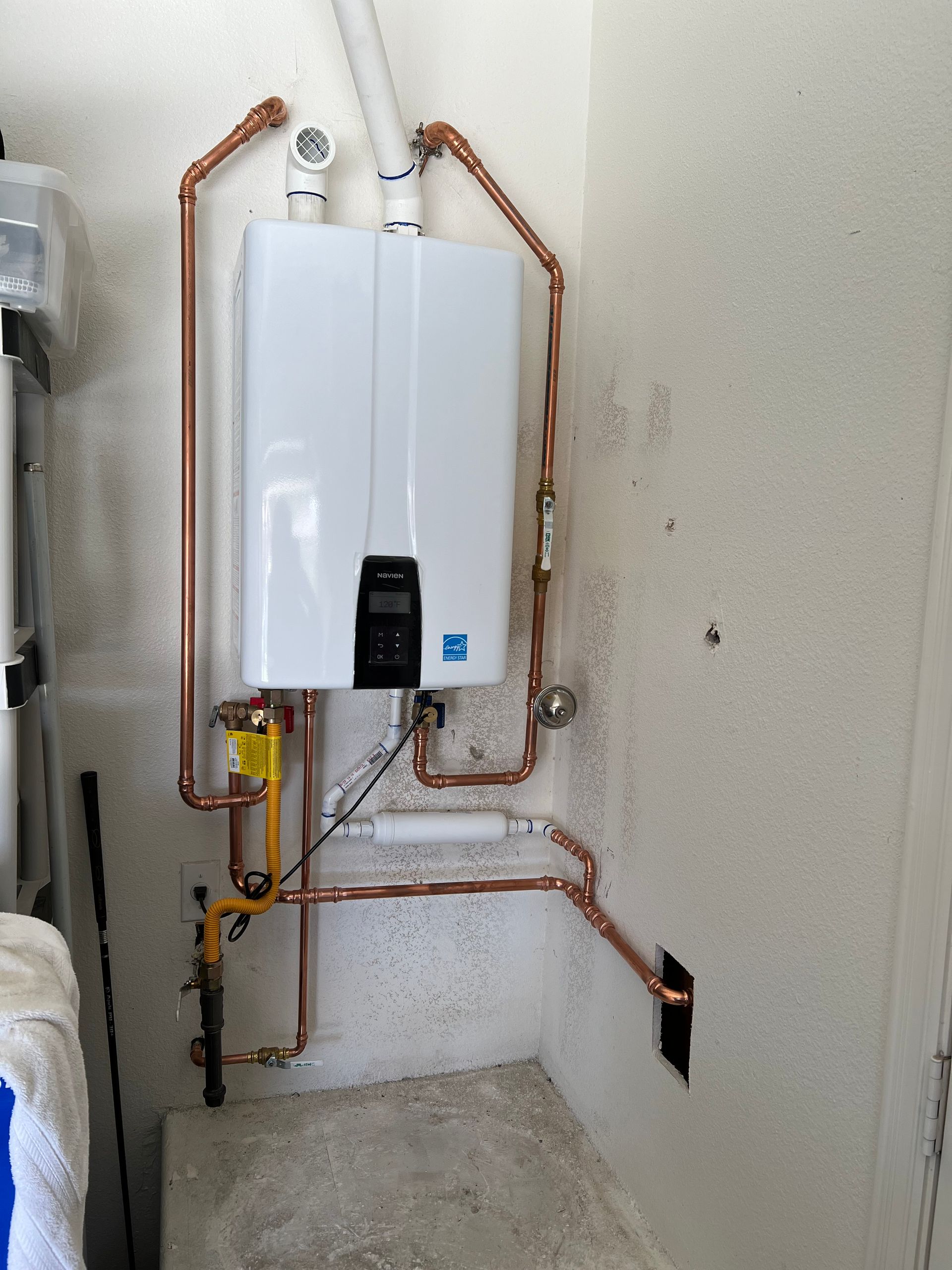 A white water heater with copper pipes attached to it